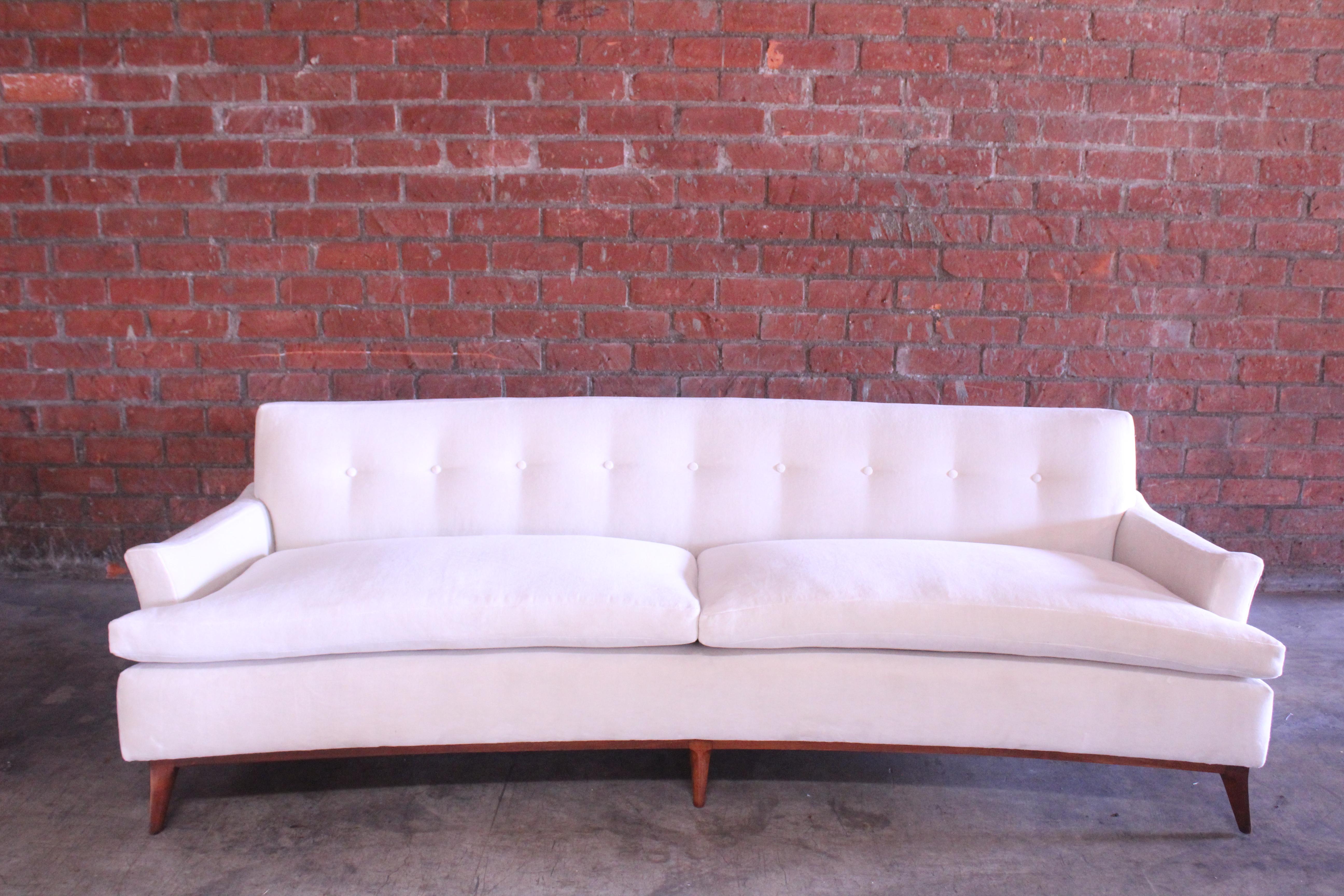 A vintage mid-century sofa from the 1950s attributed to Vladimir Kagan. This sofa has been recently upholstered in an off-white Italian cotton velvet. The sculpted walnut base has been refinished as well. In overall excellent condition.