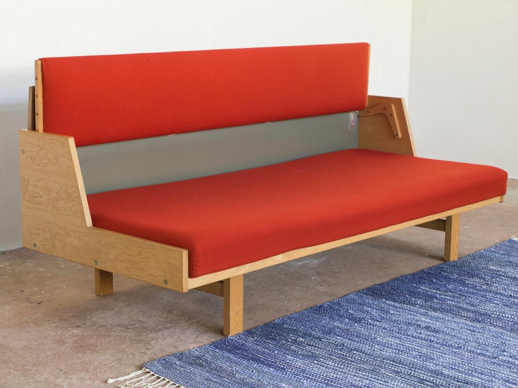 Mid-century sofa bed GE-258 designed by Hans Wegner and manufactured by Getama in Denmark in the 1960s. It is a very practical sofa: the backrest can be put up to serve as a (day)bed. The sofa is in oak with the original red fabric in very good