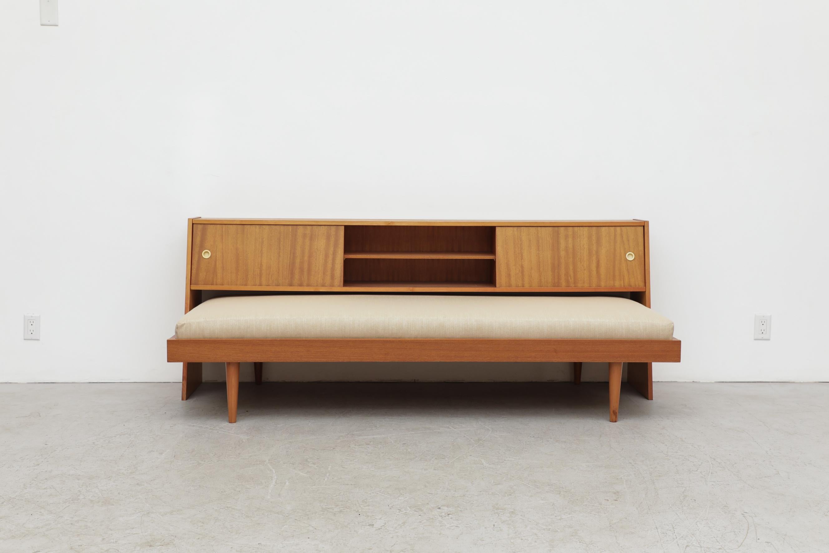Mid-Century teak daybed and matching headboard with storage cabinets and shelves. The headboard is detached, bed can easily be pushed in as a sofa or pulled out for more space as a bed. Headboard measures 76 x 15.25/8.625 x 29.625