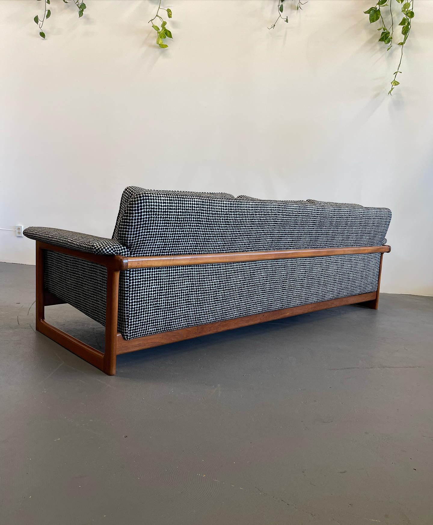 A solid teak frame that wraps the entire sofa. Newly upholstered in a bold fabric that is sure to make this a statement piece. The teak frame shows very minimal signs of wear from use.