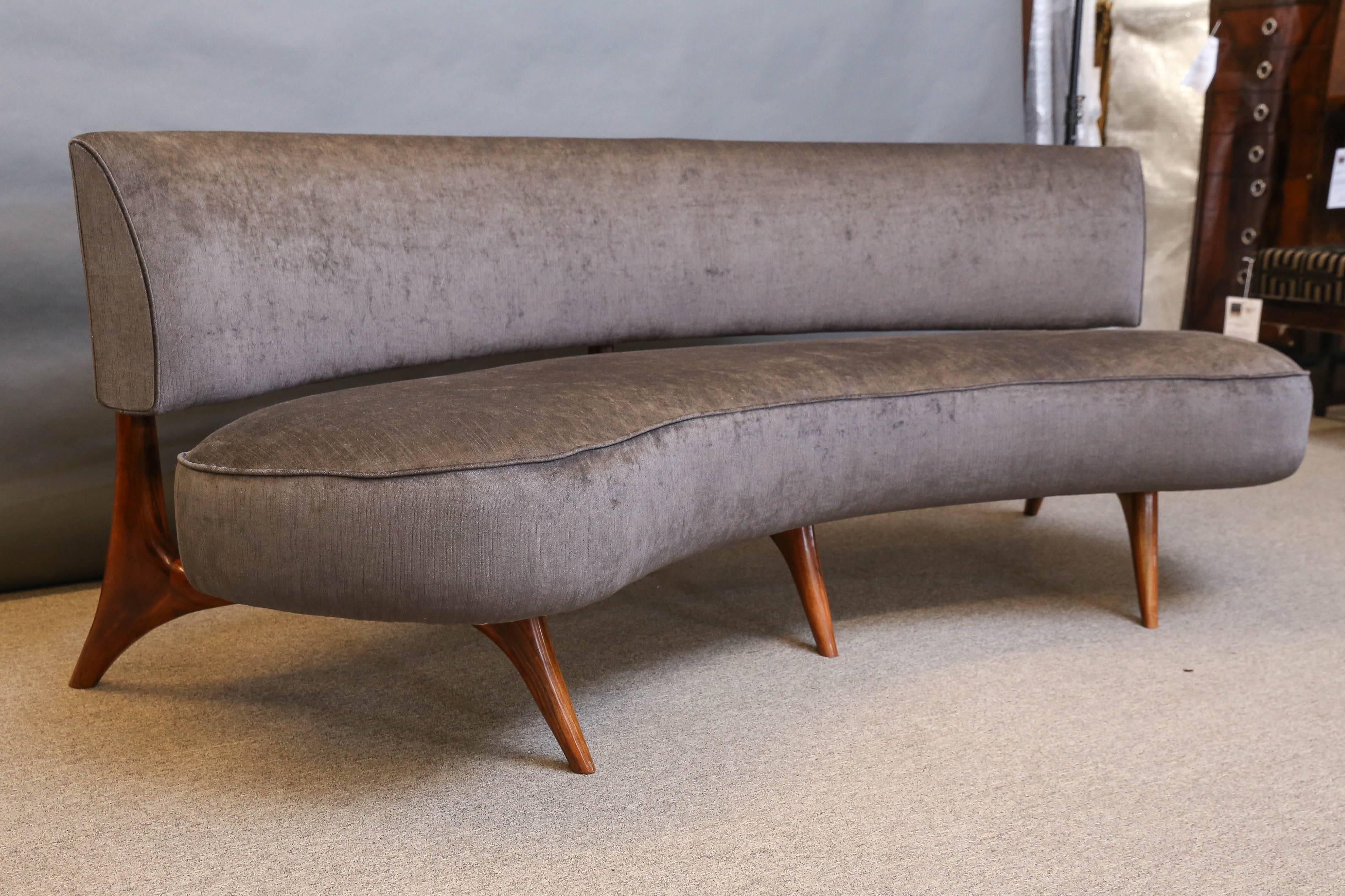The sofa has a “kidney shape” body. Sit and back supporter are separated and connected with each other with small wooden elements.
Sofa is elevated with slim walnut legs.
Newly re-upholstered with a light grey fabric. 
  Attributed to Vladimir