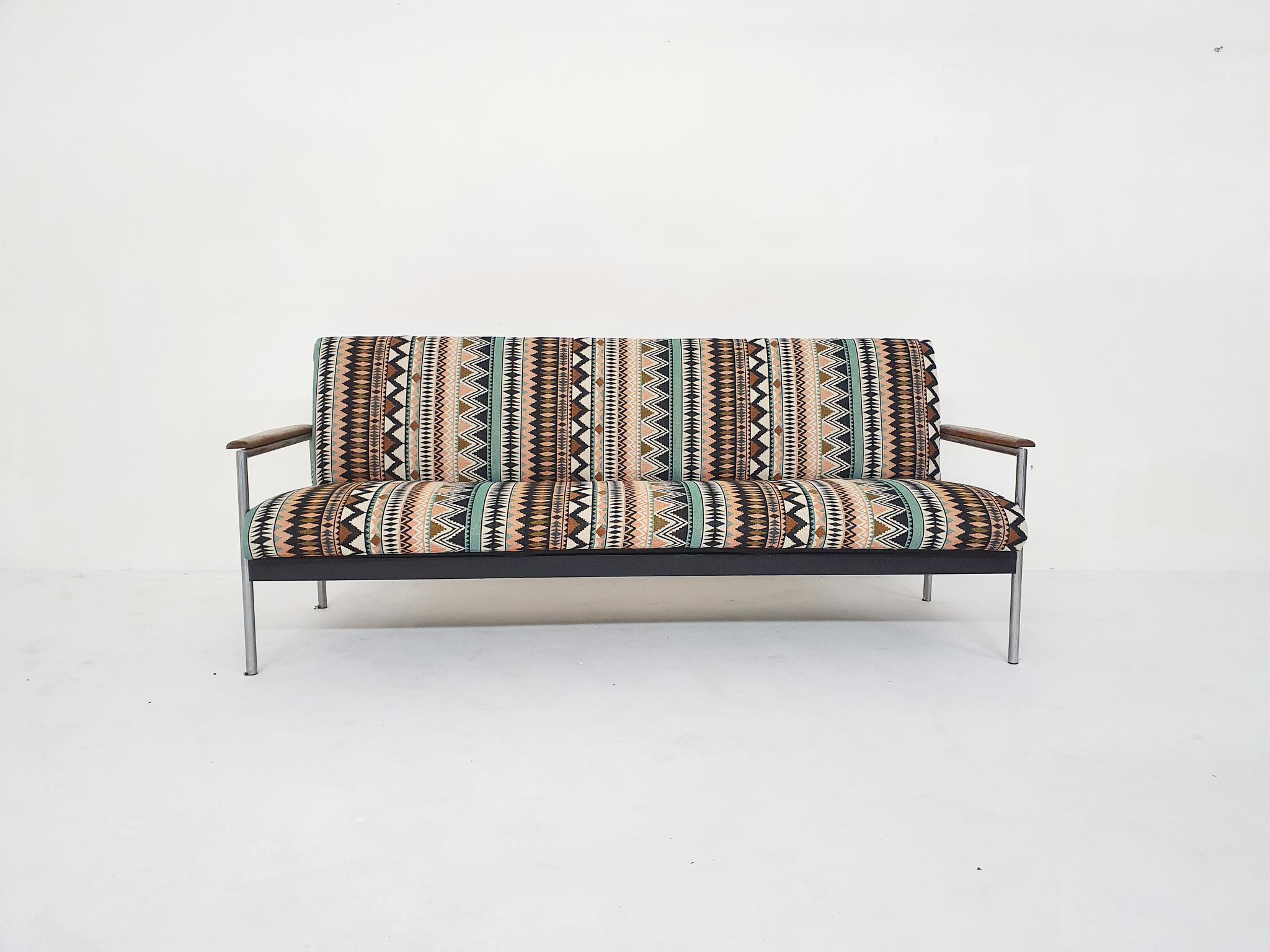 Mid-century sofa on a metal frame with wooden arm rests. We have re-upholstered the sofa with a fabric with a funky pattern.