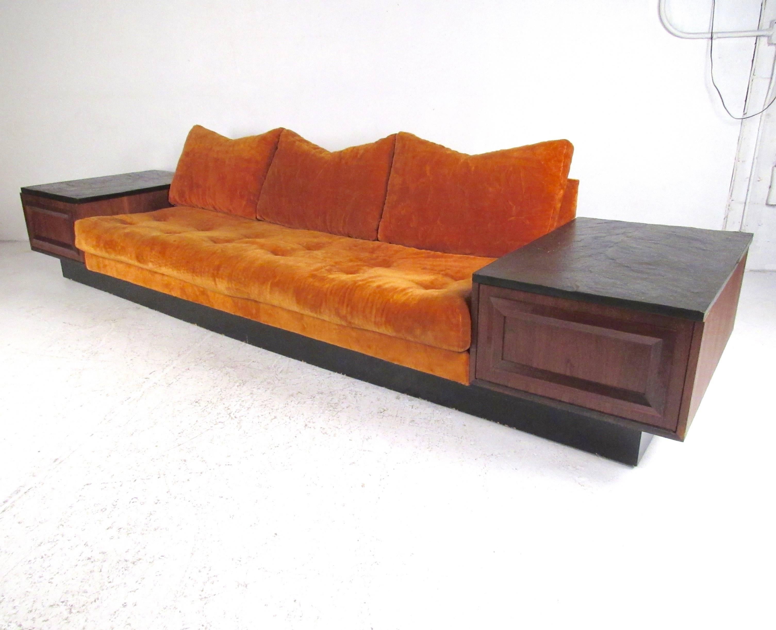 This exquisite oversized sofa features vintage fabric and offers built in walnut end tables, complete with slate stone tops. Tufted upholstery in vibrant orange make this Adrian Pearsall style sofa a substantial, comfortable, and impressive addition