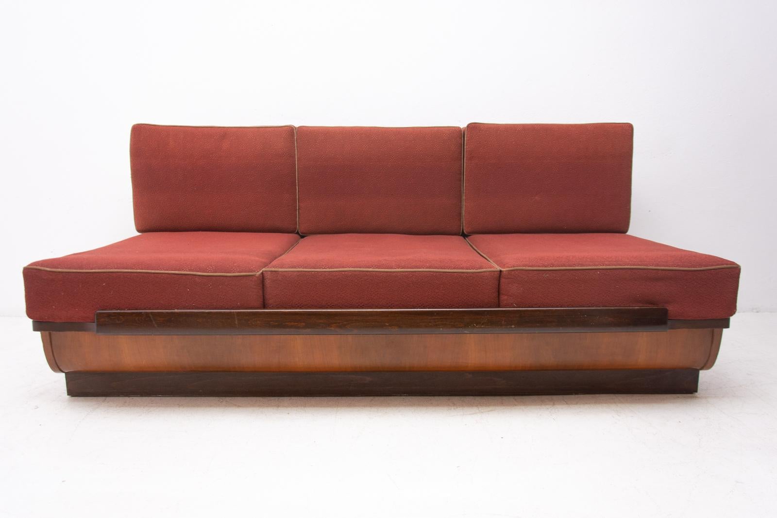Midcentury sofa bed designed by Jindřich Halabala. It was made in the former Czechoslovakia in the 1950s. This sofa features a wooden structure that is veneered in the walnut and a storage space for bedding. Sofa is adjustable for sleeping. The sofa
