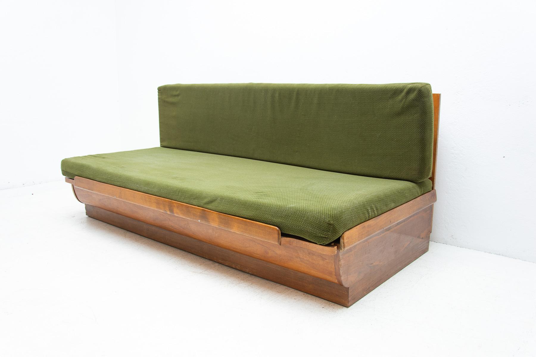 Mid century sofabed designed by Jindrich Halabala. It was made in the former Czechoslovakia in the 1950´s. This sofa features a wooden structure that is veneered in the walnut and a storage space for bedding. Sofa is adjustable for sleeping. The