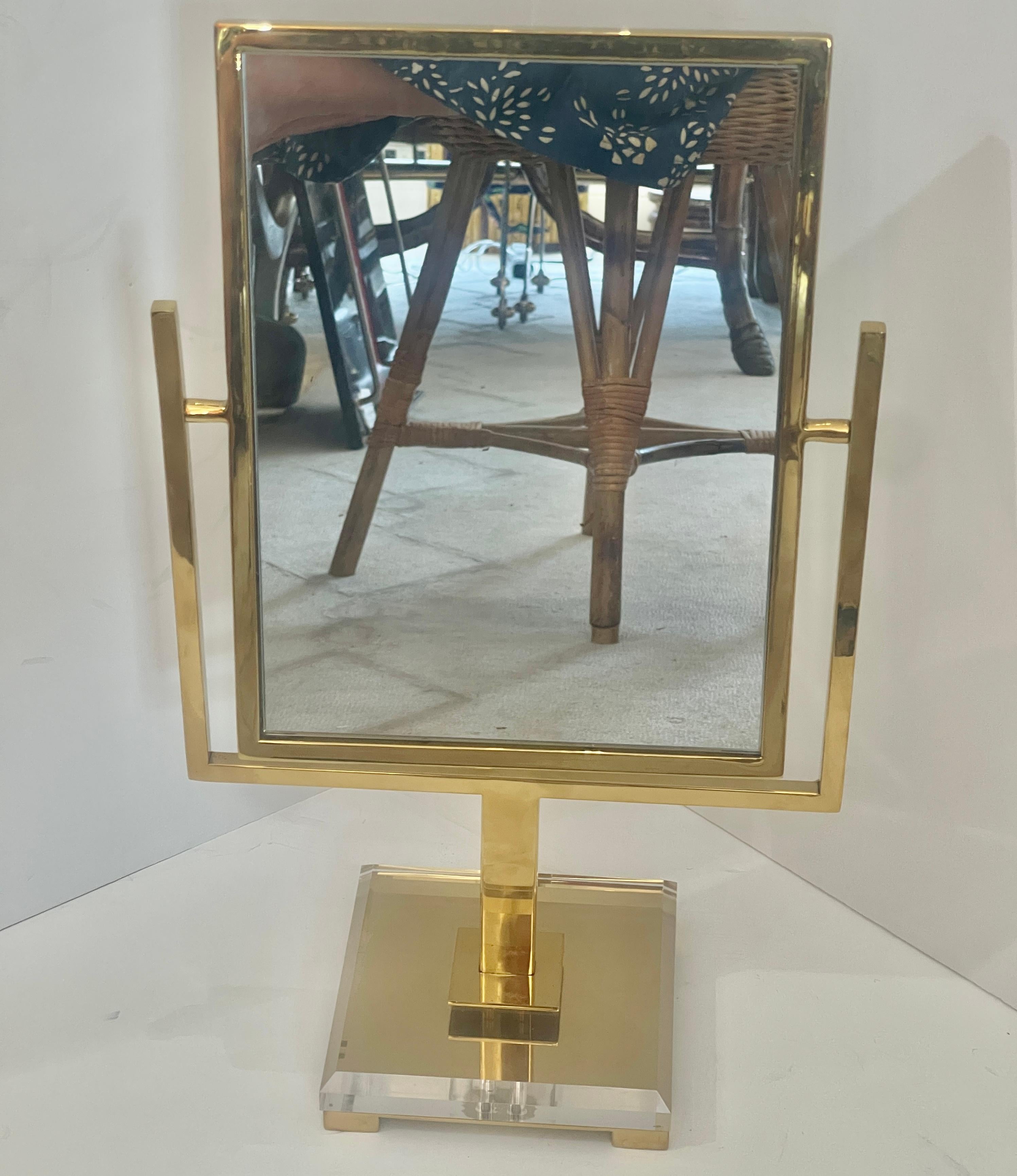 Questo specchio da tavolo per vanità in ottone massiccio e lucite del Mid-Century, anni '70, è appena arrivato per la tua nuova vanità.
Si tratta di uno specchio solido e pesante realizzato in ottone lucido su una base quadrata in lucite e ottone,
