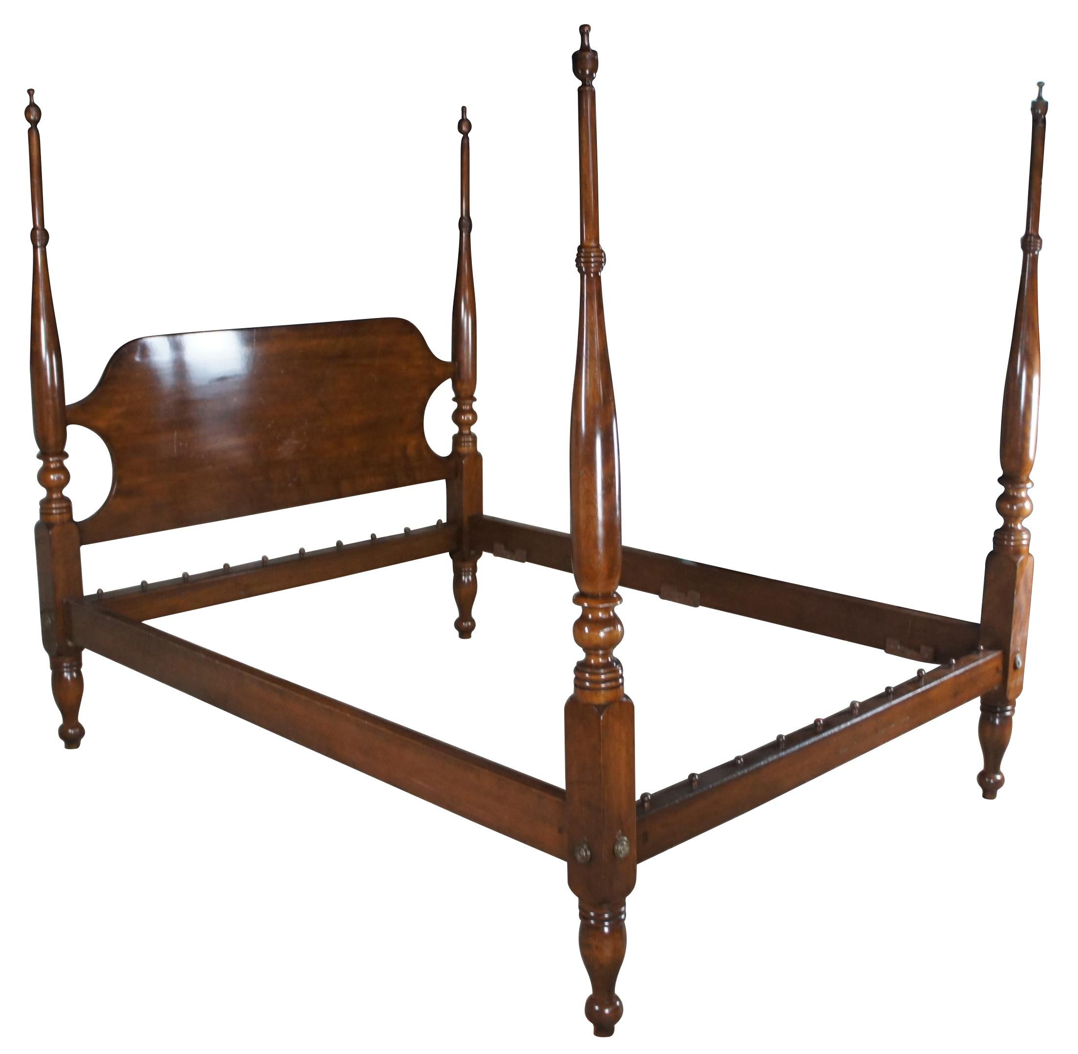 A beautiful 4 poster solid Mahogany, circa 1950s. Features a camelback headboard and long turned ribbed posts with leading to trophy finials. The bed has colonial brass plates along the corners and is supported by turned toupie or turnip