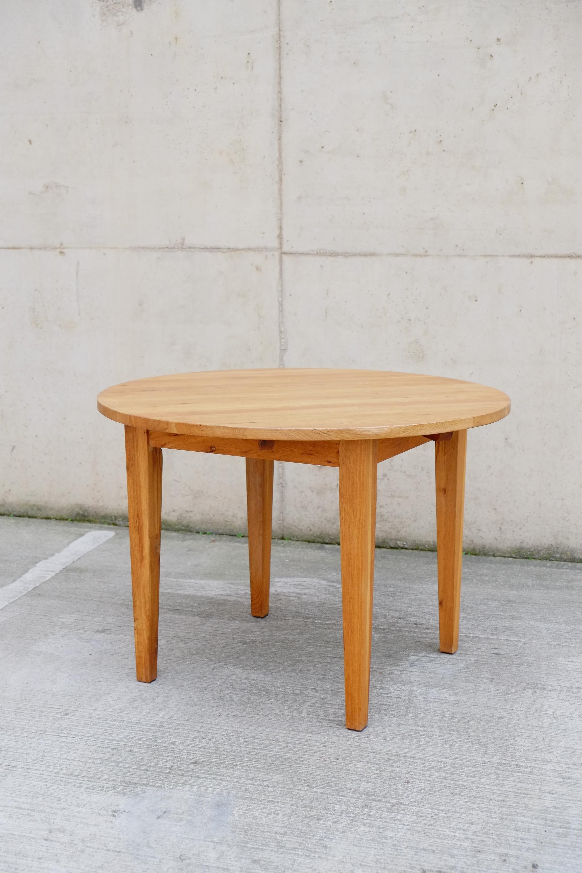 Magnifique table de salle à manger circulaire en pin massif du milieu du siècle. Cette table vintage a un magnifique ton chaud de pin avec une finition en bois naturel. Le plateau de la table est lourd et raboté, et les pieds de la table ont une