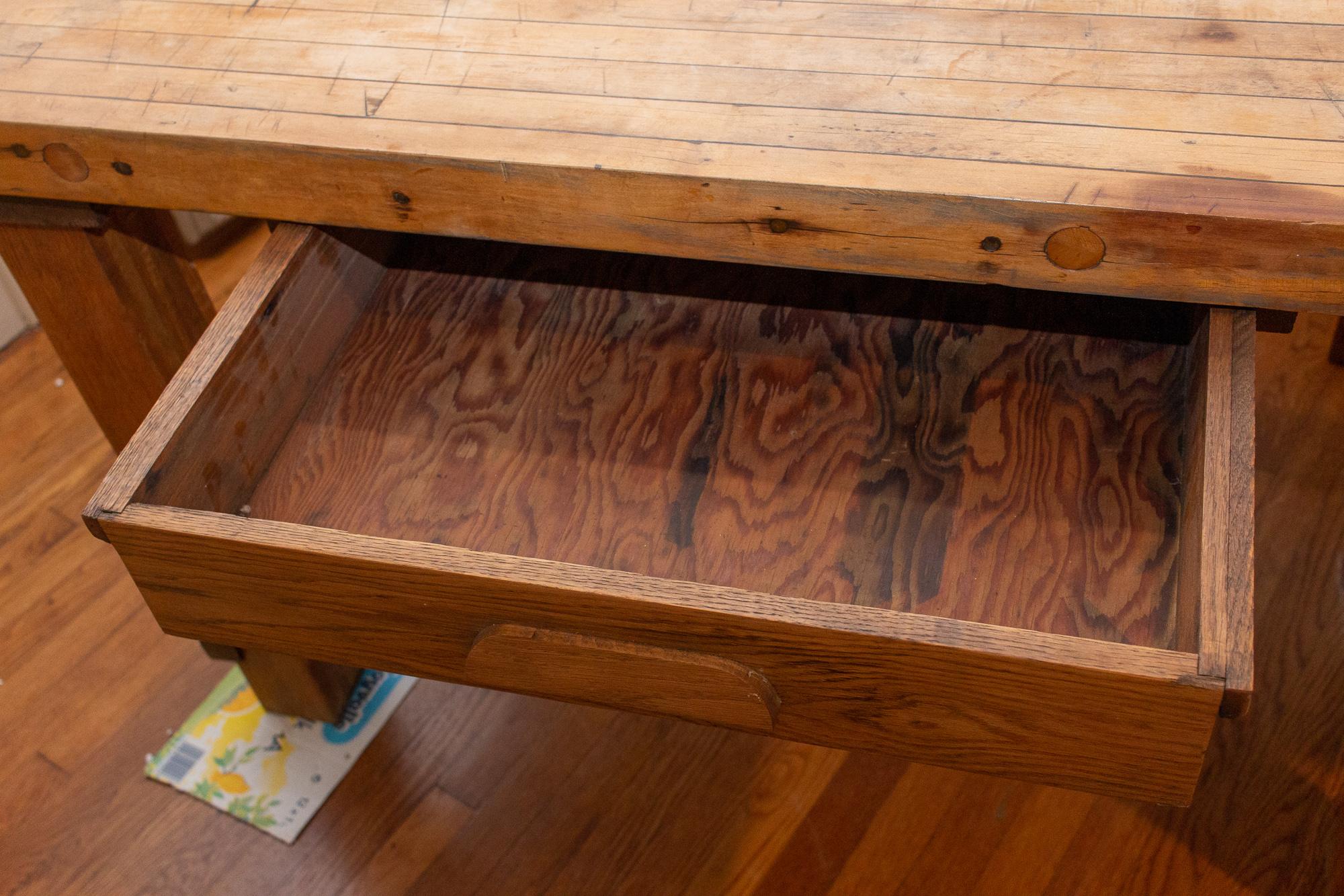 This large, vintage solid wood worktable features a butcher-block style top with two drawers. This piece would make a fantastic kitchen worktable or island, which can double as an eating area. Each leg is removable, making it much easier to