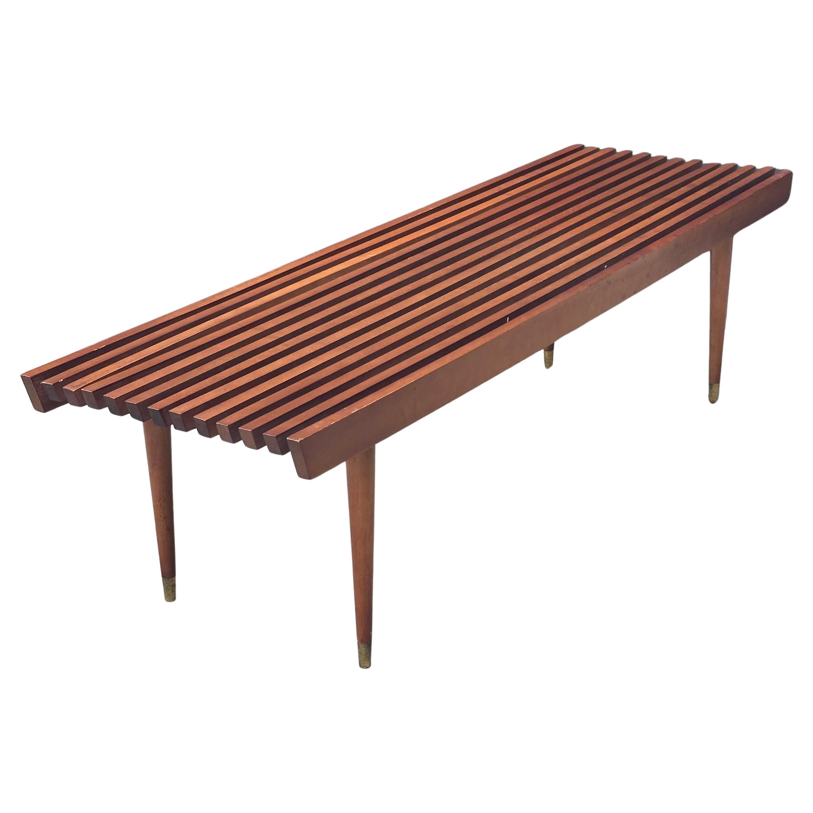 Mid-century solid wood (possibly birch) platform slat bench by Nasco of Yugoslavia, circa 1960s.  The piece is solid and sturdy with brass capped tapered legs that can be removed for easy storage or shipping.  Nice angle edge end cut; can be used