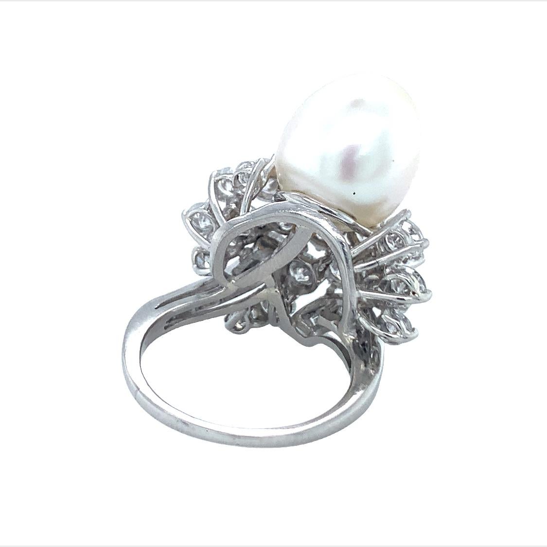 One Mid-Century South Sea pearl and diamond platinum ring featuring one oval shaped, white South Sea pearl measuring 12 millimeters in diameter. The ring is enhanced by 30 round brilliant and straight baguette cut diamonds weighing a total of 4.95