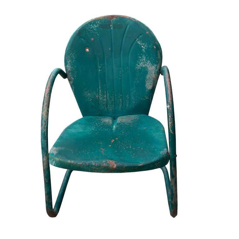 A pair of mid-century green metal patio or garden chairs. In the south, these patinated beauties are usually found around ranches or farms. Lovingly patinaed over time, they have a lifetime of stories they could tell. This pair was sourced from a