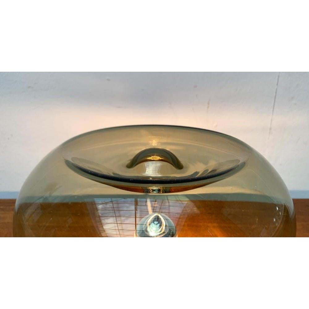 Lampe en verre de l'ère spatiale.

Une source lumineuse fonctionnelle avec un caractère d'objet. L'élégant corps du luminaire est conçu en verre fumé transparent. Le verre repose sur une base chromée et est fixé par trois vis à tête plate. Le verre