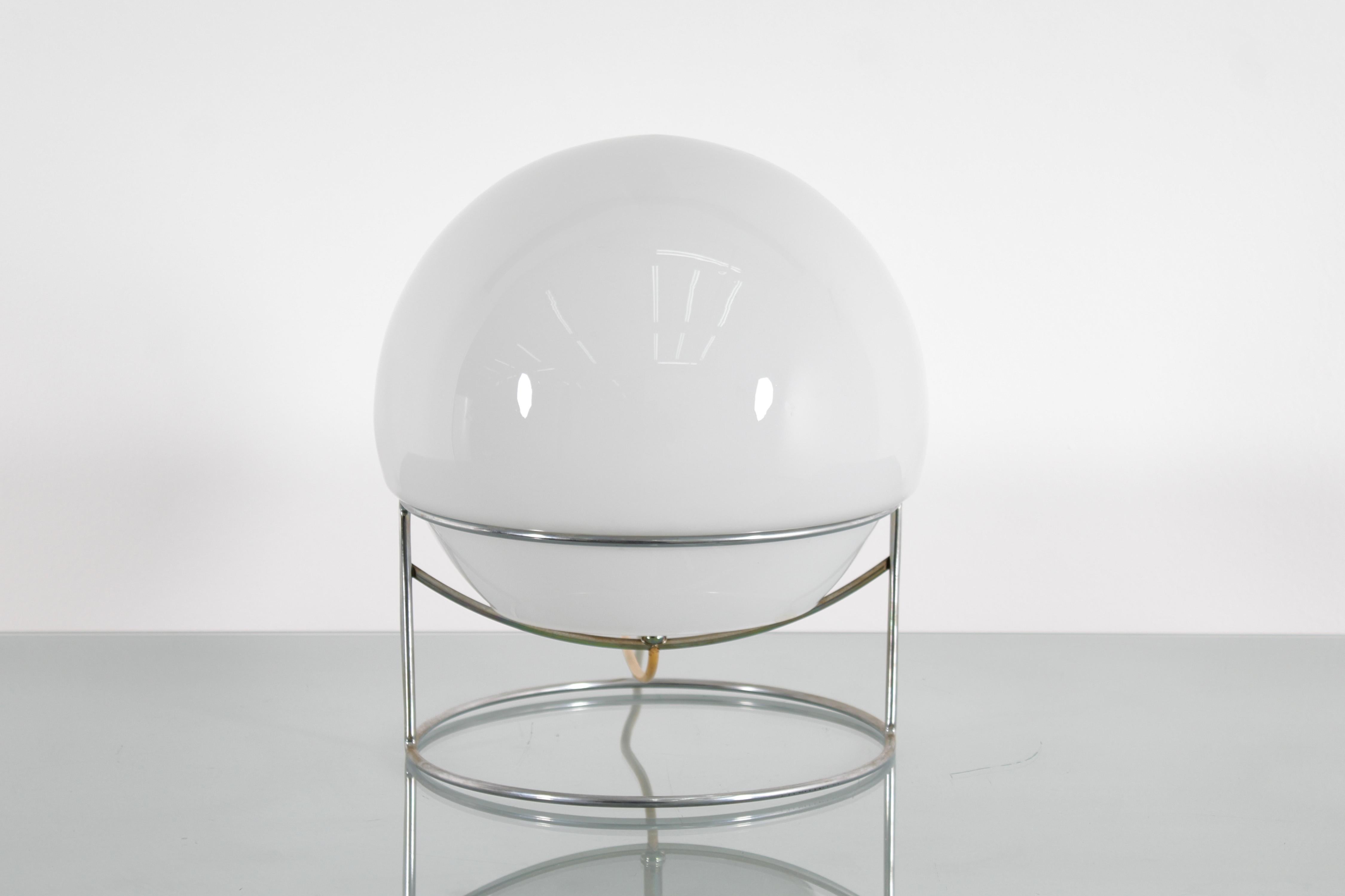 Sehr schönes Beispiel einer Space Age Tischleuchte mit einer kreisförmigen Struktur aus verchromtem Stahlstab, auf dem der halbkugelförmige Diffusor aus milchig weißem Glas sitzt. Italienische Produktion im Stil von Carlo Nason, aus den 70er Jahren.