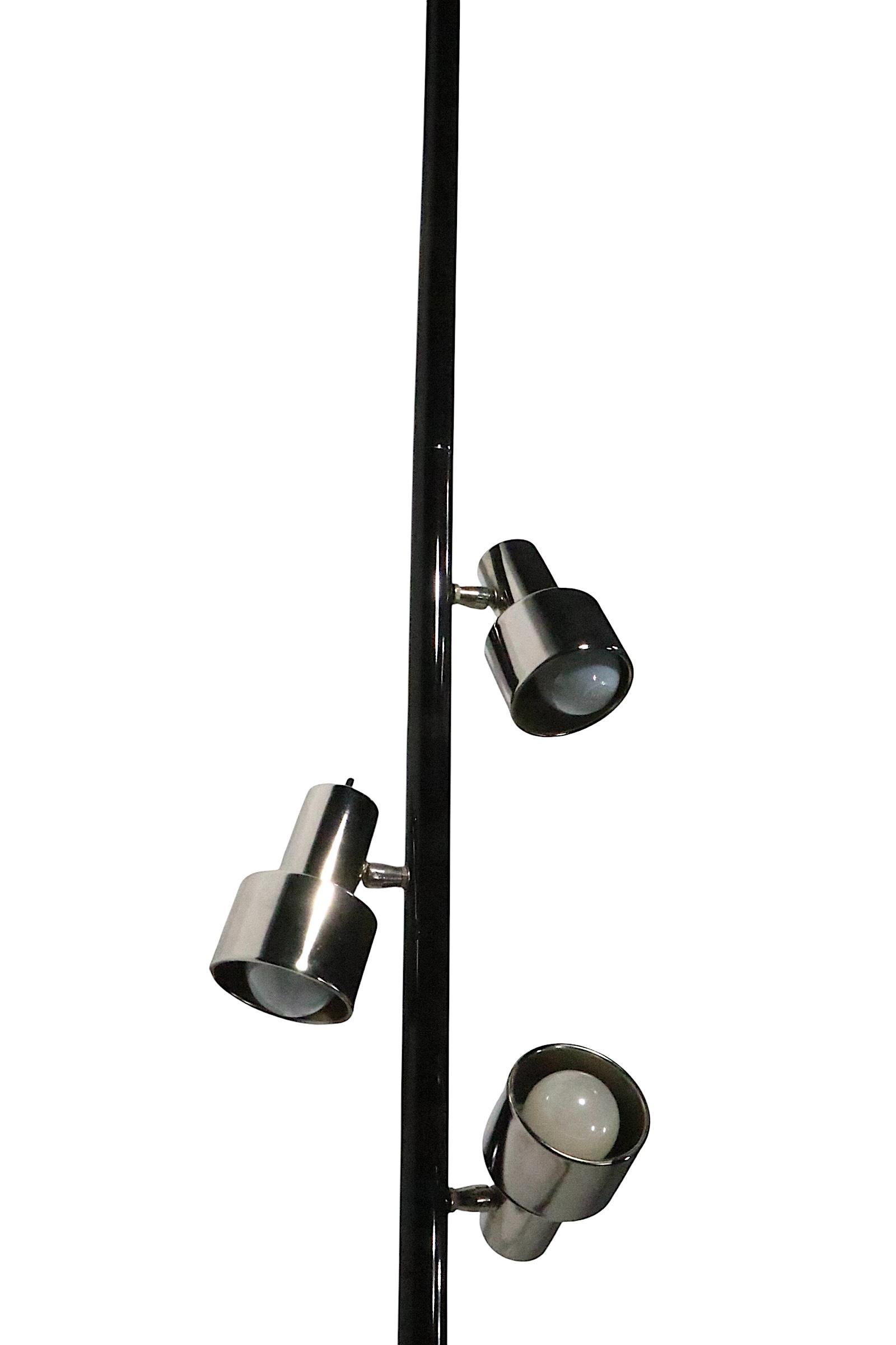 Exceptional mid century tension pole floor lamp, having a black center post, with three bright chrome shaded lights. Each light is adjustable in position, and has its own on/off switch. The lamp is in very good, clean, original, working and ready to
