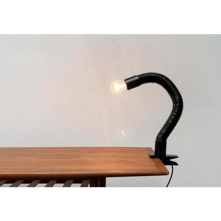Space Age Schwanenhals table clamping lamp.

The lamp shows a futuristic Space Age Design with a flexible neck made of a black plastic hose. The lamp has a clamp for assembly on a table top, shelf board etc. European Plug (up to 250V).The wiring of