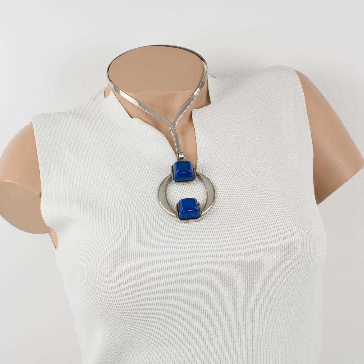 This stylish Mid-Century Modern Space Age collar necklace has a geometric pendant. The stainless steel rigid neckband is designed with a futuristic medallion attached to it. That pendant is ornate with dimensional cobalt blue resin cabochons. There
