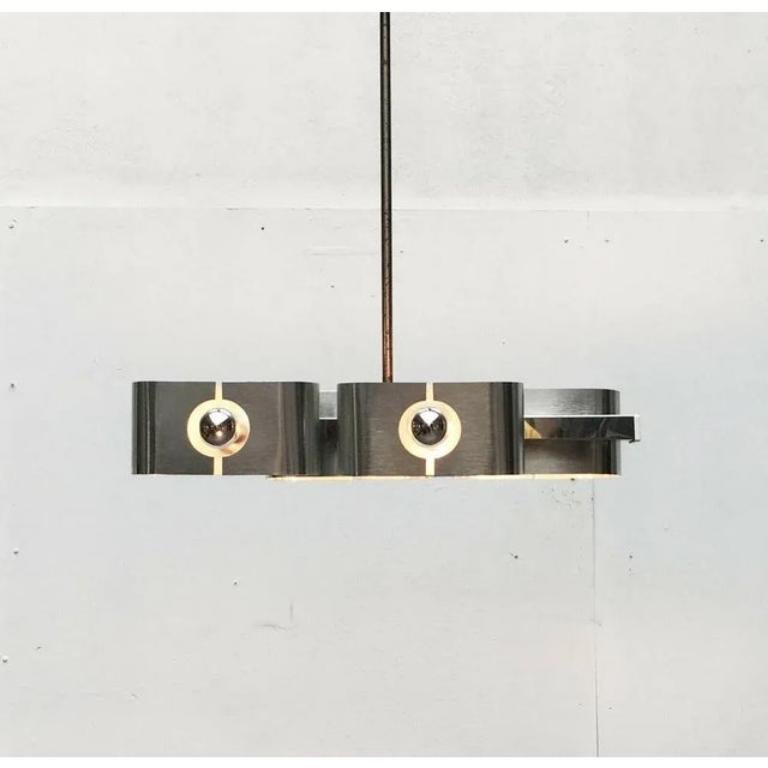 Piccolo ma impressionante candeliere dell'A Space AGE proveniente dalla Francia degli anni '70.

La simmetria e la linearità di questa lampada seguono un linguaggio di design piuttosto minimalista. Seduto su un binario cromato in basso. Una versione