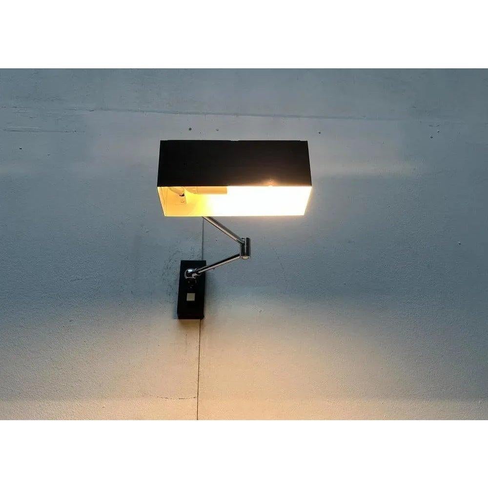 Lampada da tavolo minimalista di metà secolo del produttore tedesco Hoffmeister shine.

Il design si basa sulla famosa lampada da parete con fenicottero di Bur (Bünte & Remmler). La testa della luce ha la forma di un semplice cuboide aperto sul lato