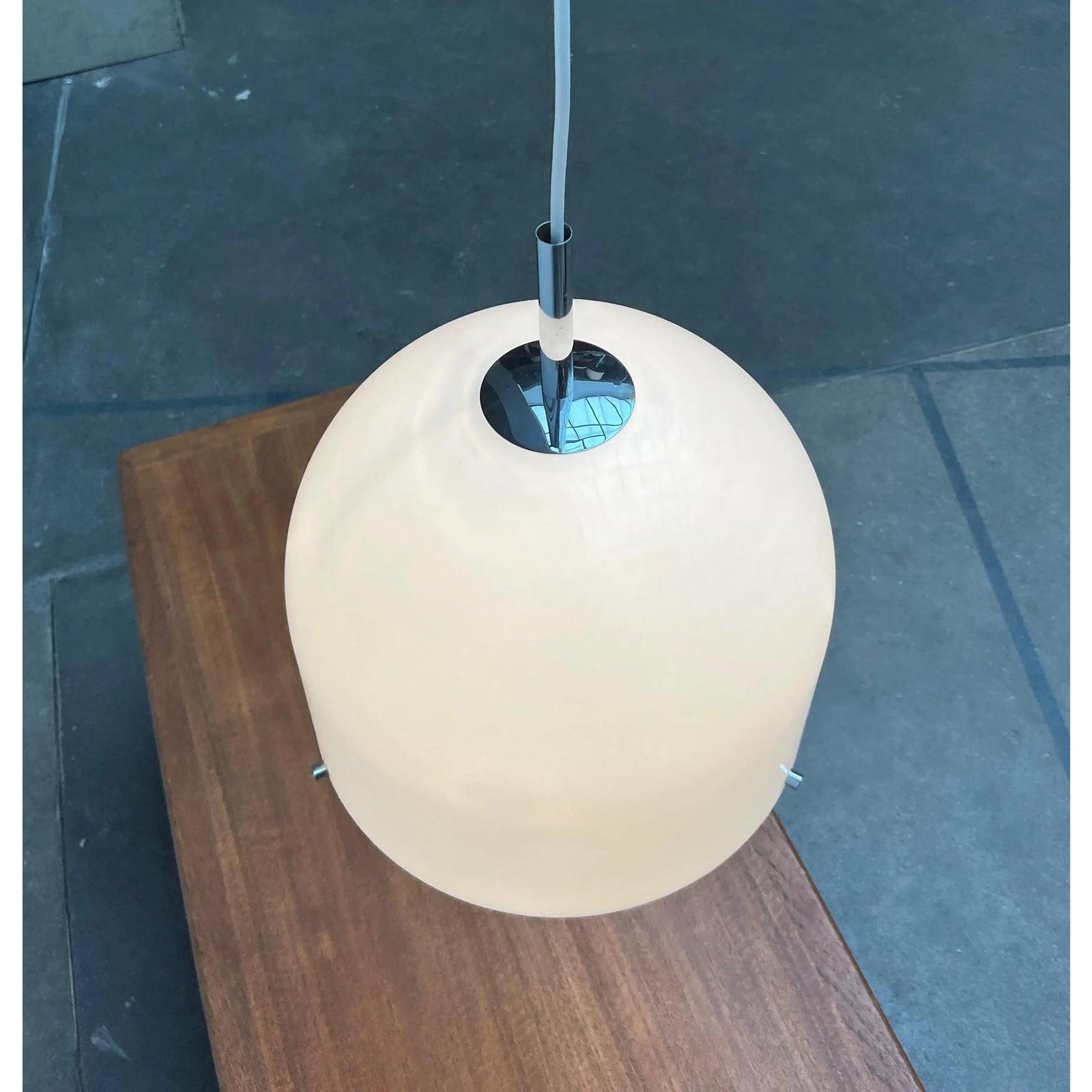 Imponente lampada a sospensione A Space AGE di WILA.

Il corpo della lampada è a forma di campana ed è composto da due elementi. Alla base del cappuccio superiore c'è un cappuccio più piccolo che chiude la parte inferiore. Questo viene montato a