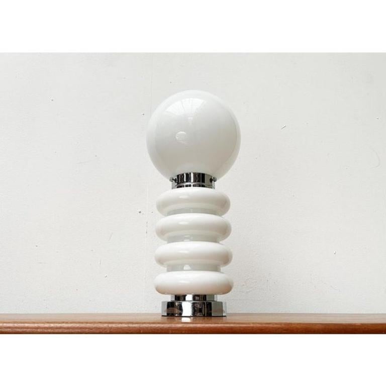 Imposante lampe de table ou sur pied d'après un design de carlo nason des années 1960.

Cette lampe impressionne par sa matérialité en chrome et en verre ainsi que par son langage de conception organique. Le diffuseur inférieur en verre avec les
