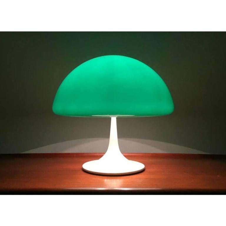 Rara lampada da tavolo della manifattura italiana Guzzini basata su un disegno di Luigi Massoni degli anni '60. Qui si tratta della prima edizione con una base a tromba in un unico pezzo e nel raro colore verde.

Il paralume a forma di fungo è