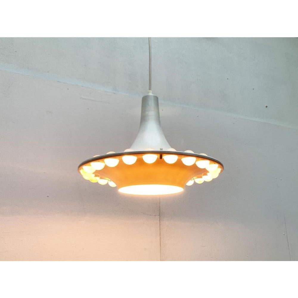Imposing pendant lamp with bright acrylic balls.

A minimalist design with an elaborate ornamentation. The umbrella shows a simple trumpet shape, which it walks and rejuvenates again. The lower funnel has a large opening through which the light exit