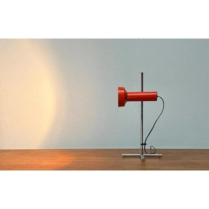 Rare Space Age table lamp from Targeti with a striking foot.

A simple design with a technical design language. The light head has a classic radiant form and is painted in orange. It can be adjusted and turned on the central chrome rod in height.