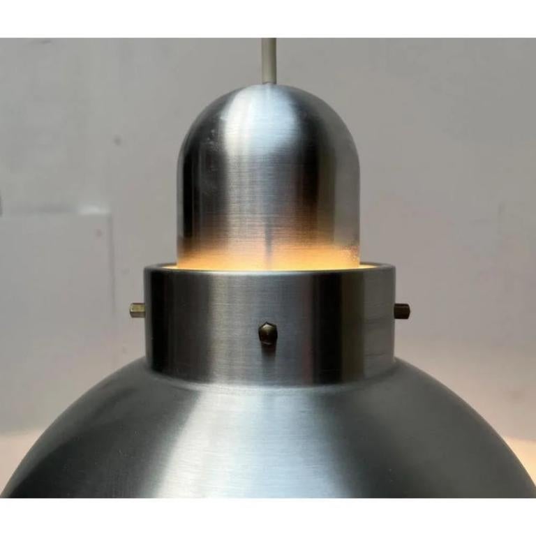 Semplice lampada a sospensione in alluminio.

Un design minimalista. Il corpo del Luminaire è in alluminio. L'interno è dipinto di bianco per riflettere meglio la luce. Il dettaglio speciale è la giunzione tra l'ombrello e il Luminaire. La