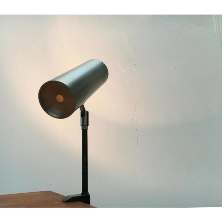 Mid Century clamp lamp.

The simple cylindrical shape of the lamp head is striking. The head can be aligned using a joint. The lamp is mounted using a heavy clamp. The lamp is in very good condition with signs of wear. European Plug (up to 250V).