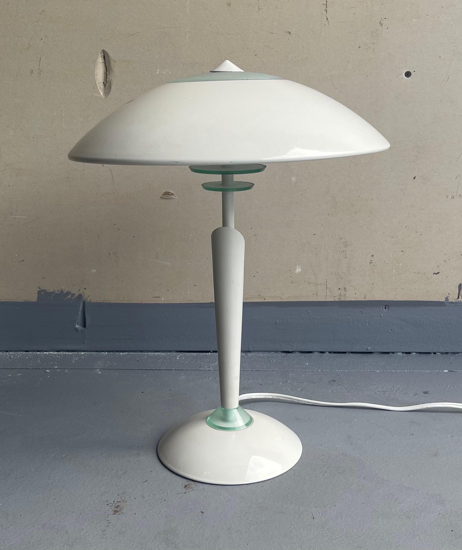 A very cool mid-century space age saucer table lamp, circa 1970s. The lamp has a white finish with glass accents and a three-way lamp that can be adjusted by touching the base. It is in very good vintage condition and measures 13