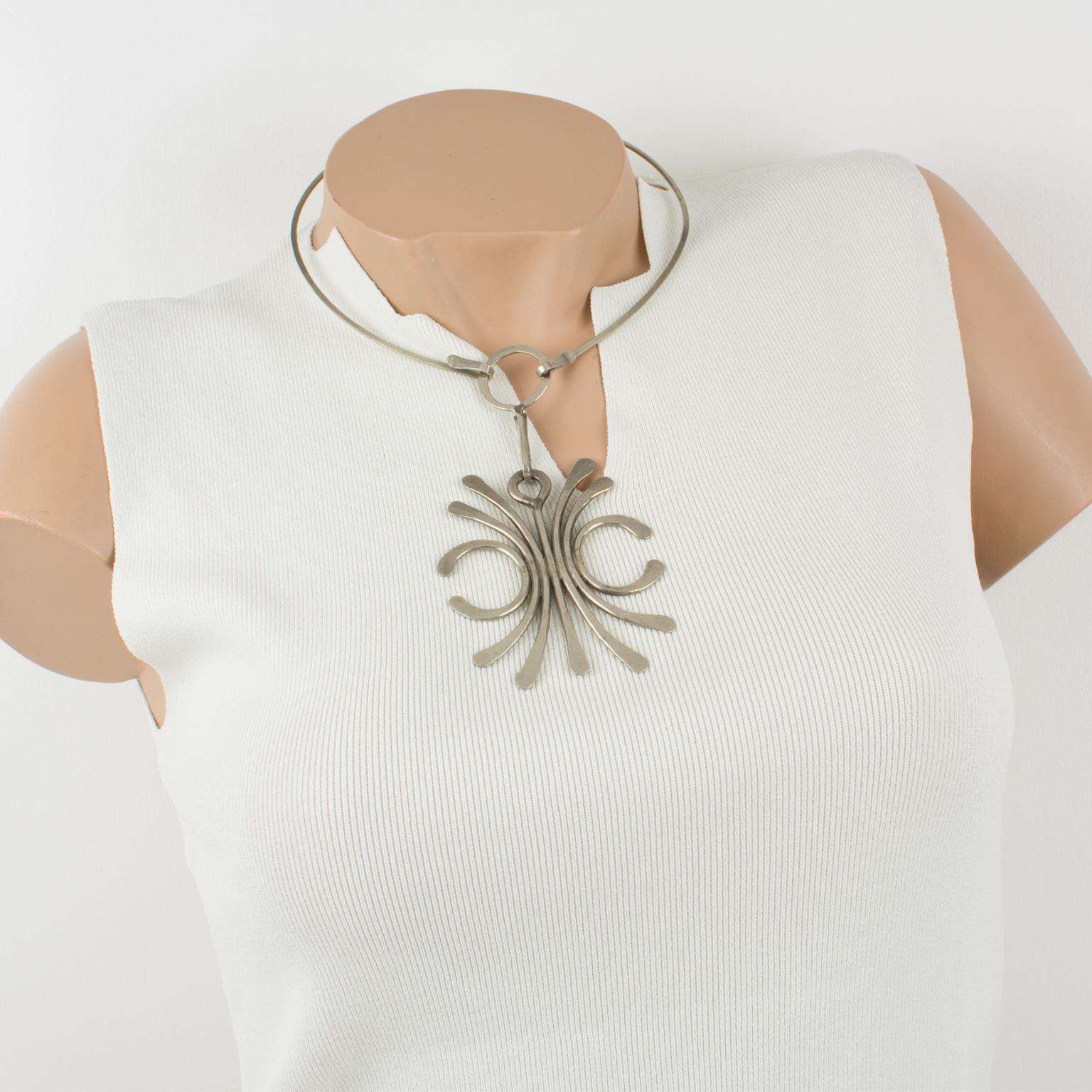This spectacular Mid-Century Modern Space Age collar necklace has an extra-long pendant. The choker features a stainless steel rigid neckband, ornate with a massive geometric pendant, in stainless steel wire with a slightly hammered surface finish.