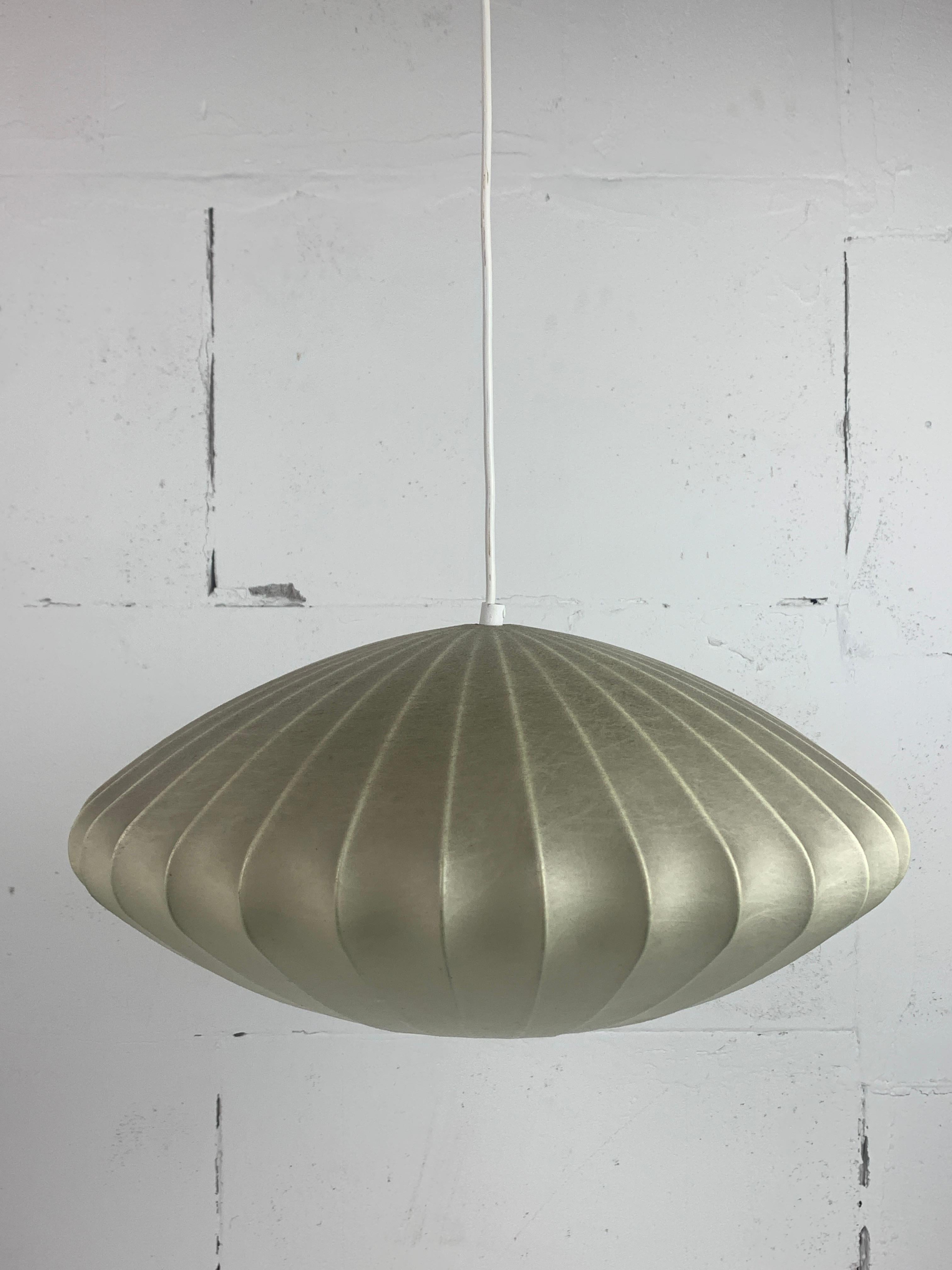 Ce magnifique pendentif en forme de cocon rappelle également la soucoupe à bulles de George Nelson. Souvent attribuée à Achille Castiglioni, elle a probablement été réalisée par Goldkant Leuchten en Allemagne.  La résine du cocon est dans un bel