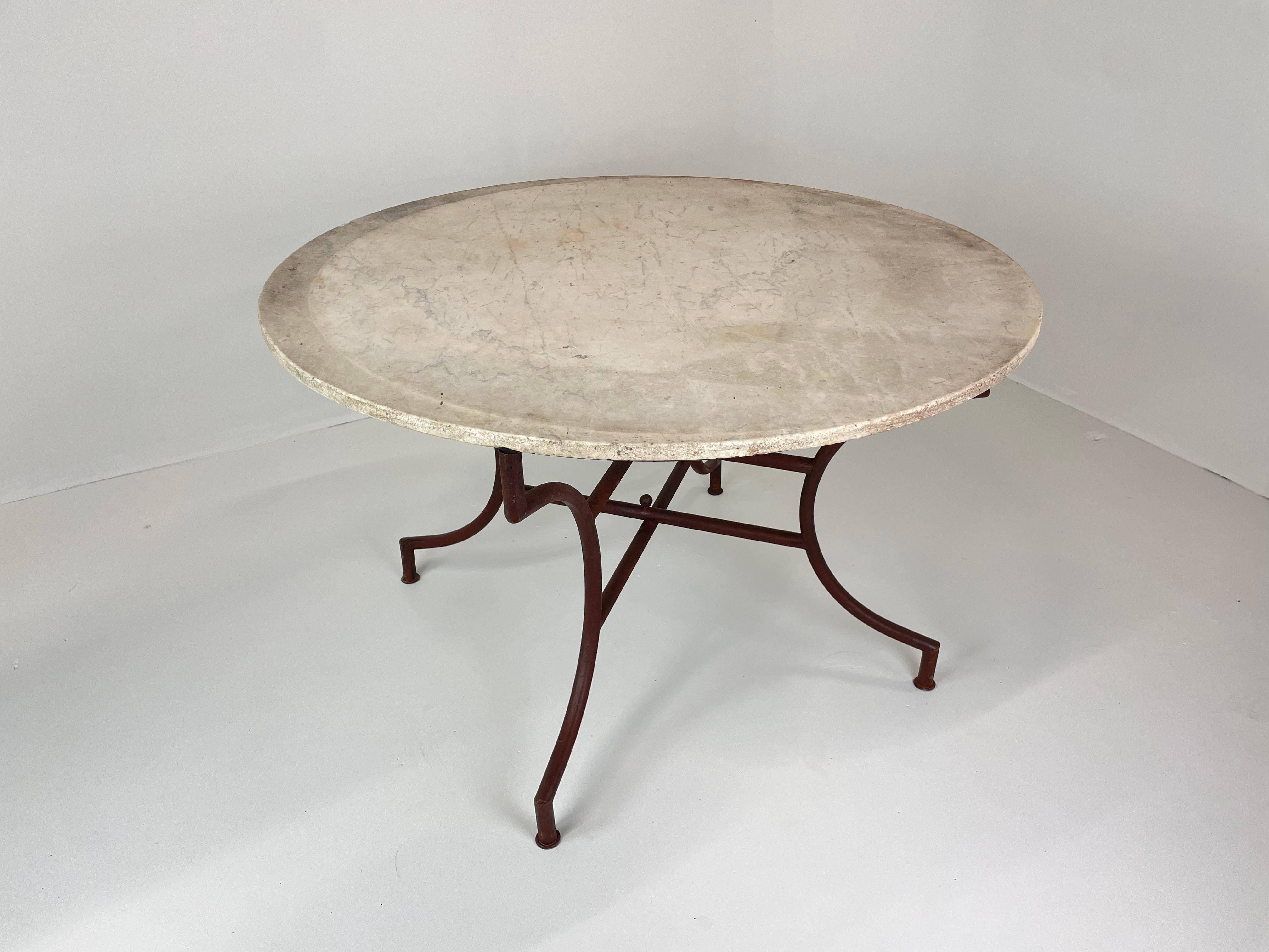 Superbe table espagnole du milieu du siècle avec un plateau circulaire en marbre de Carrare reposant sur une base en fer forgé à la main. Le cadre en fer est élégamment courbé, relié par un châssis central, et conserve sa patine d'origine usée par