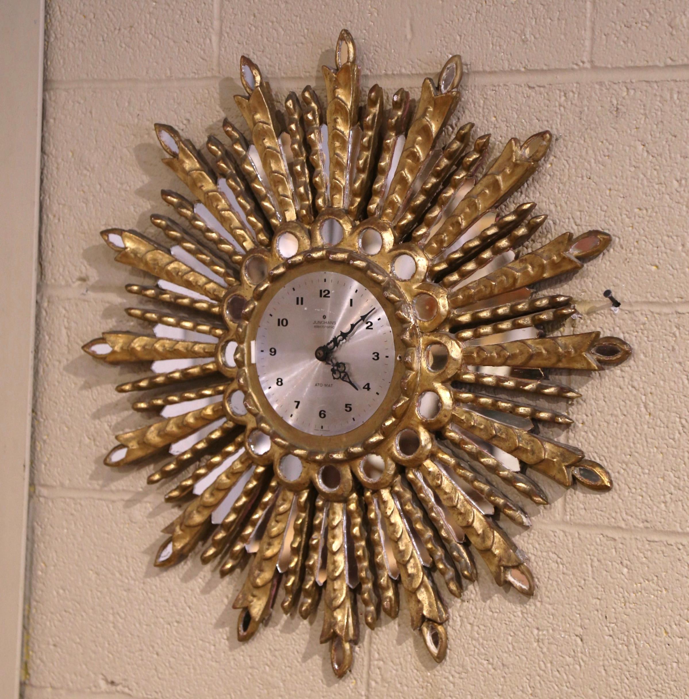 Bring a radiant touch to your home with this eye-catching gilt wood sunburst battery operated clock. Hand-carved in Spain circa 1970, the vintage clock features a circular center timepiece made in Germany, framed by mirrored insets and gilded,