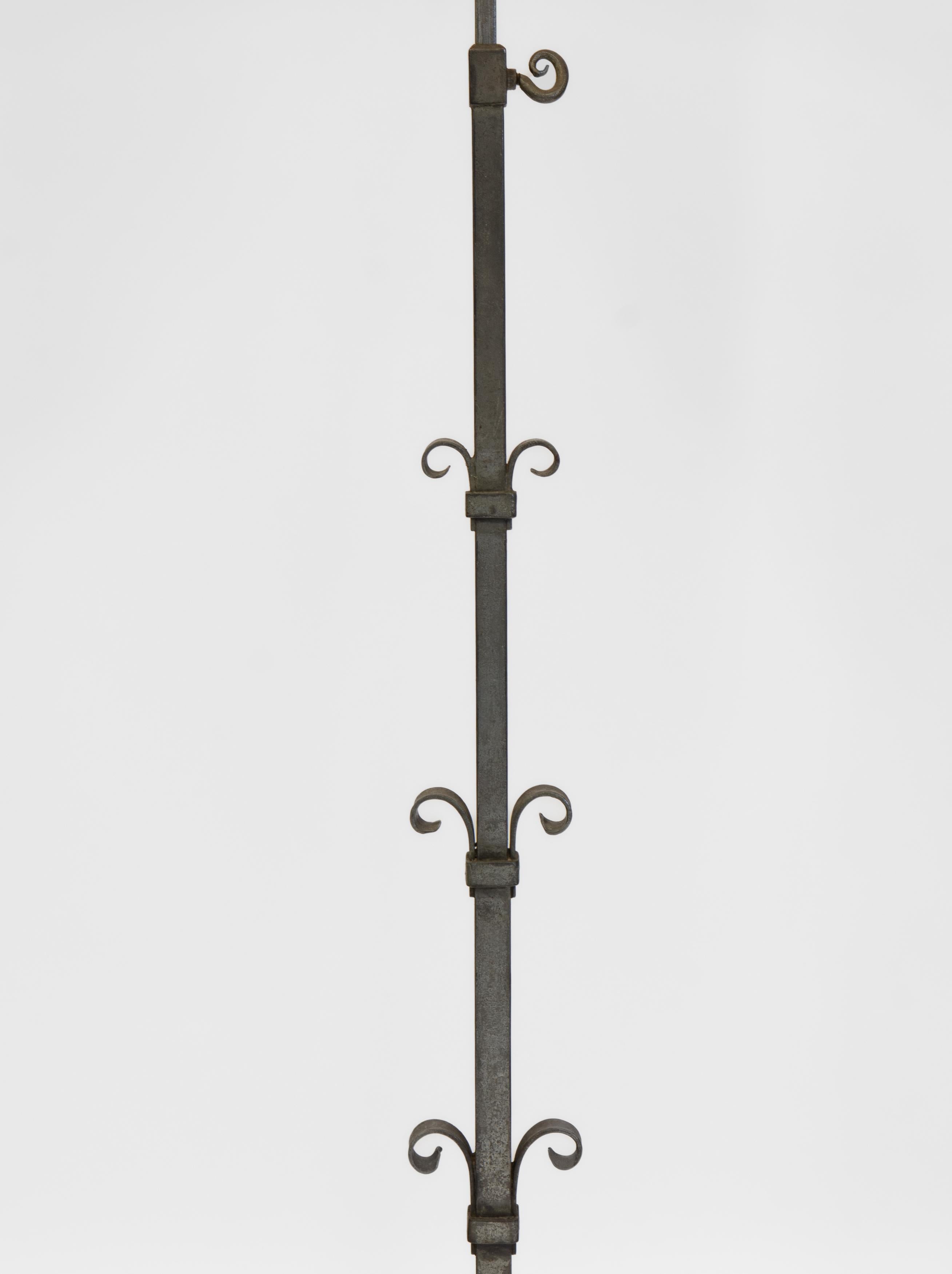 A mid-century Spanish forged iron height-adjustable floor lamp. Circa 1960.

Forged iron design on a square upright, patina to the metal with age. Structurally very sound and the height adjustment works very well. 

The lamp has been re-wired and a