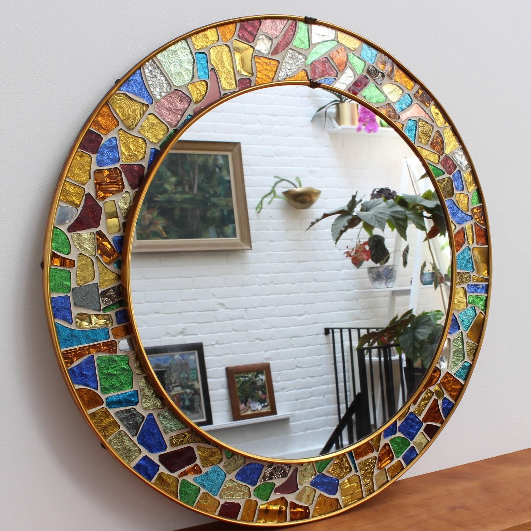 Splendid midcentury circular brass mirror with colorful mosaic surround. Made in the style of Antoni Gaudí's 'Trencadís' technique involving irregularly-shaped hand-cut-glass tiles in different colors. Spanish origin, circa 1960s. A short video clip