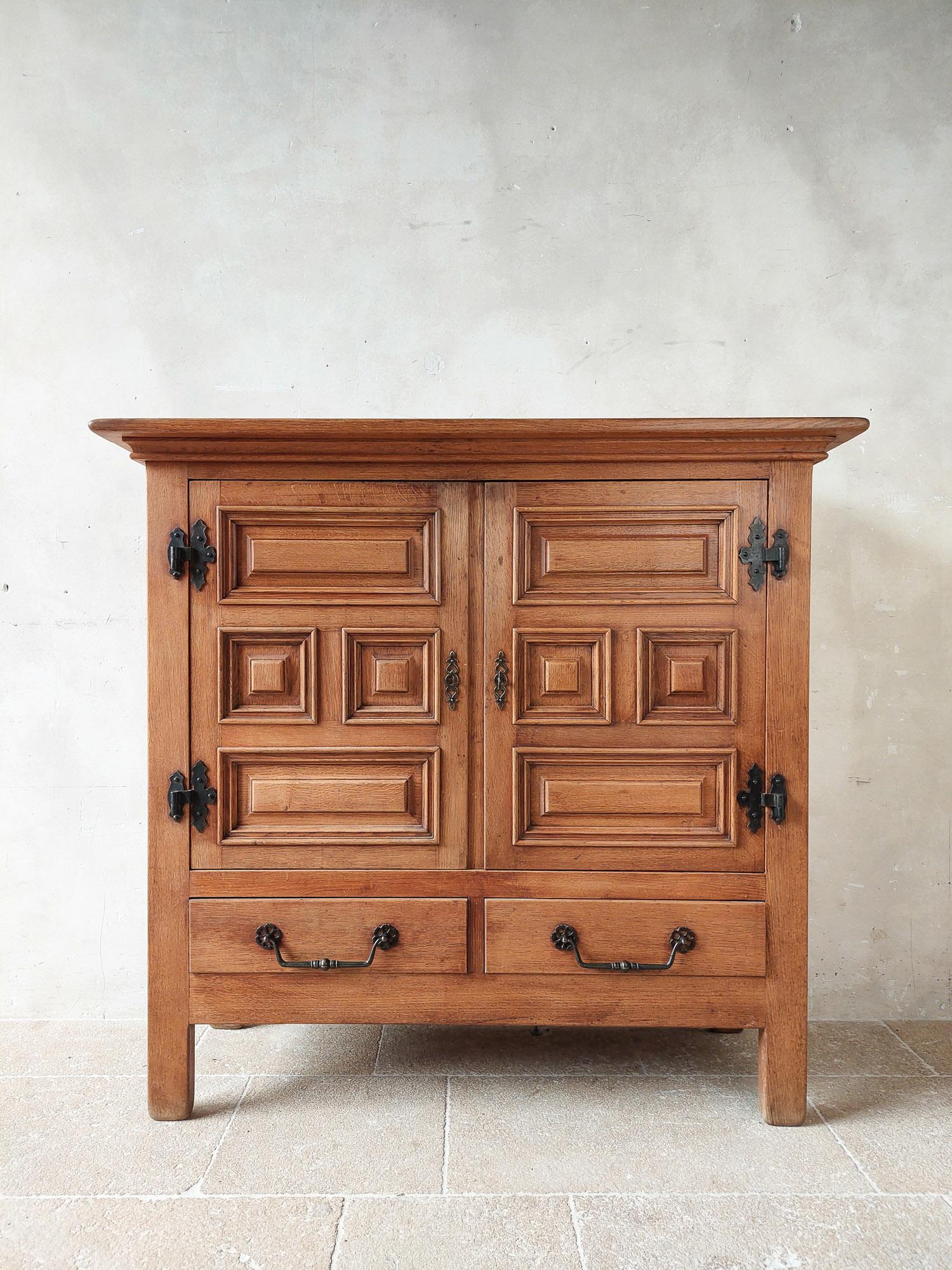 Mid-century Spanish oak cabinet, 1950s. Beautiful solid oak high sideboard in Spanish rustic modernist style. With two doors and two drawers decorated with geometric panels and wrought iron hardware. This oak 'high board' has a beautiful light brown