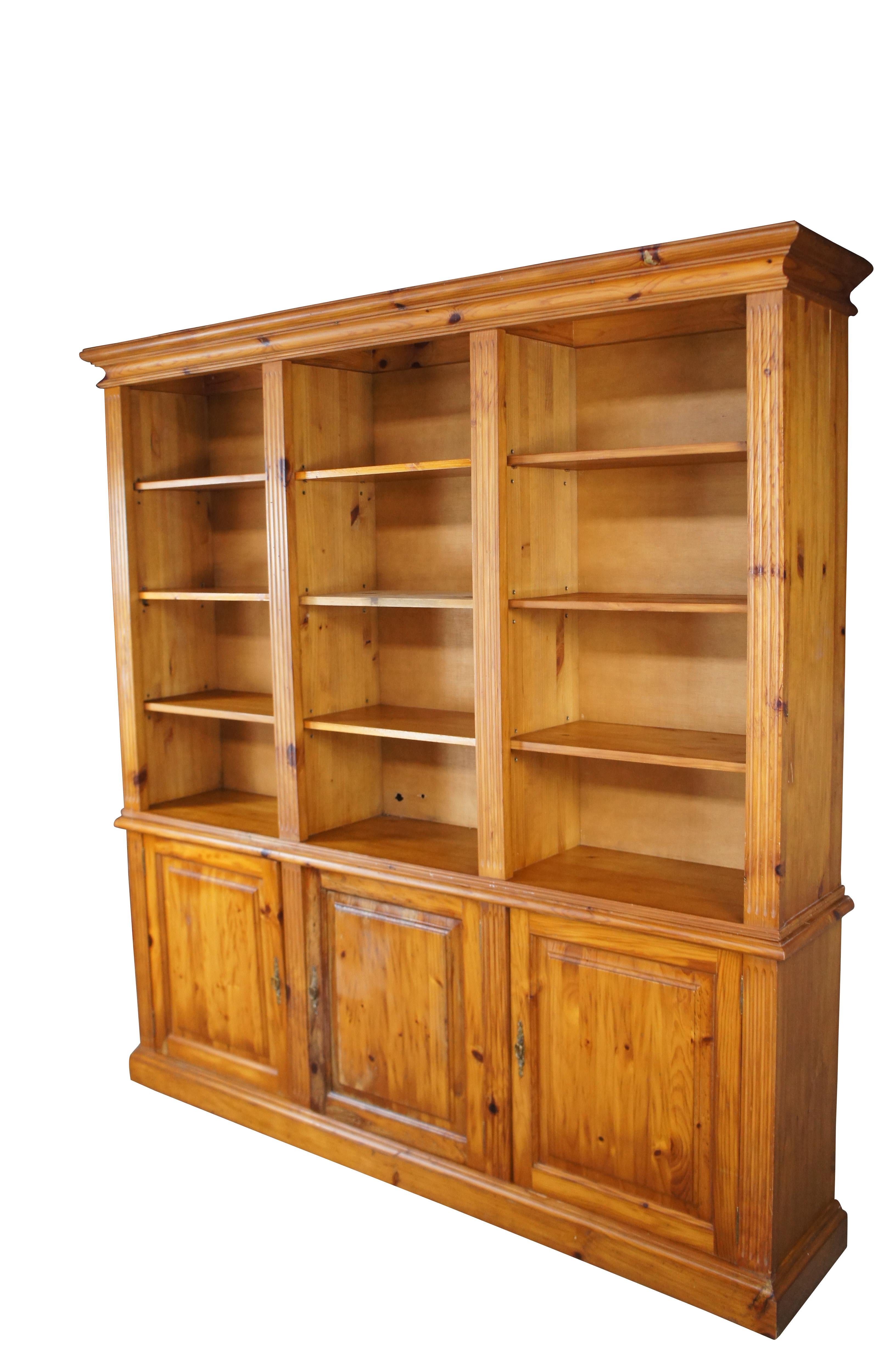 A lovely European pine Bookcase by Alberto Carvers of Spain, circa 1960s. Features a solid pine construction with nine adjustable shelves flanked by fluted columns.  The two piece cabinet is supported by a three door base with an interior shelf in