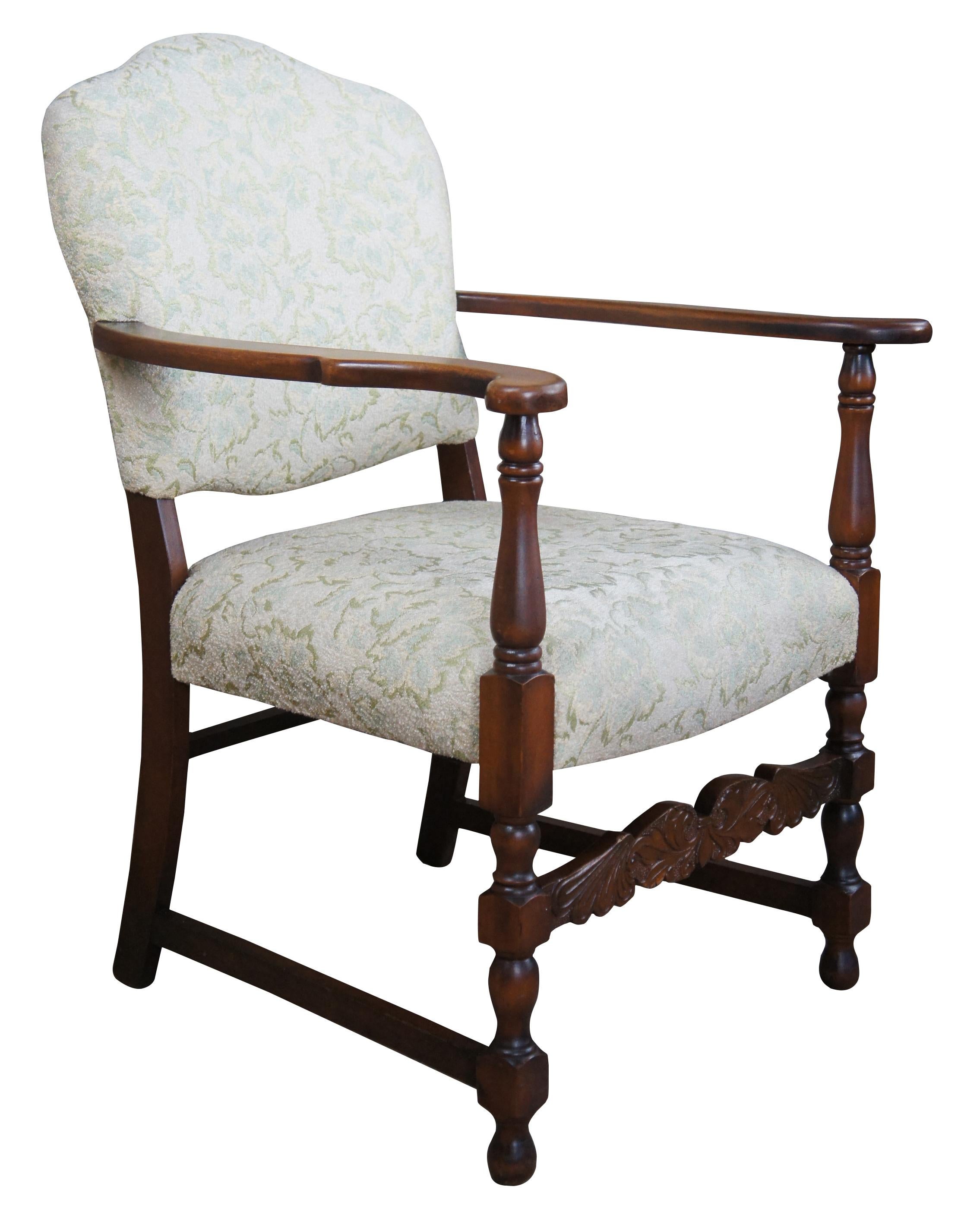 Mid 20th century Spanish revival arm chair. Made from mahogany with flared arms, turned supports and a carved fluer stretcher. The chair is upholstered along the seat and back with a floral pattern.