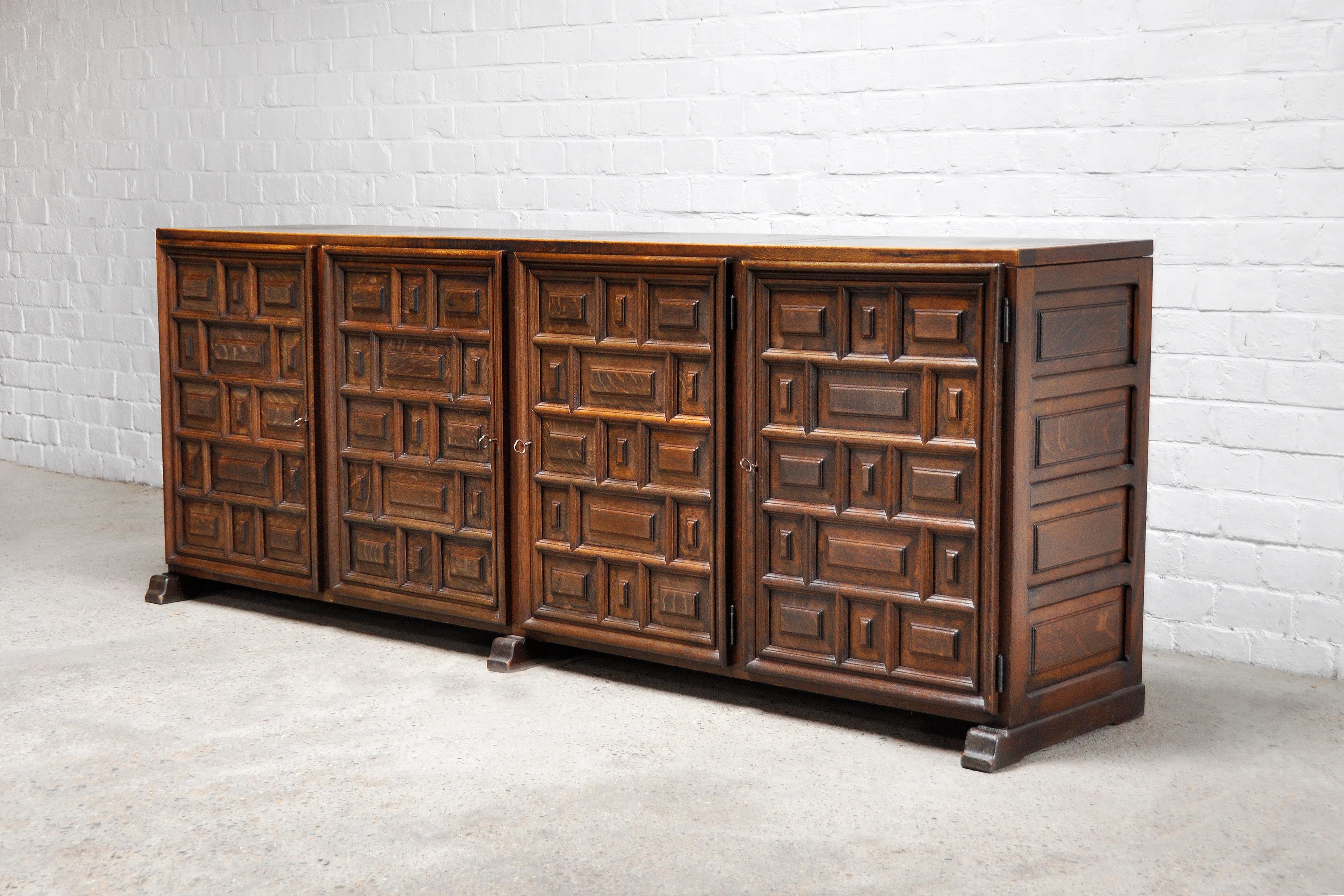 A Spanish 'Brutalist' Sideboard with profusely panelled front. The use of multiple geometric and deeply fielded panels creates a striking effect with a strong and decorative expression. The warm/dark oak gives this piece a rustic