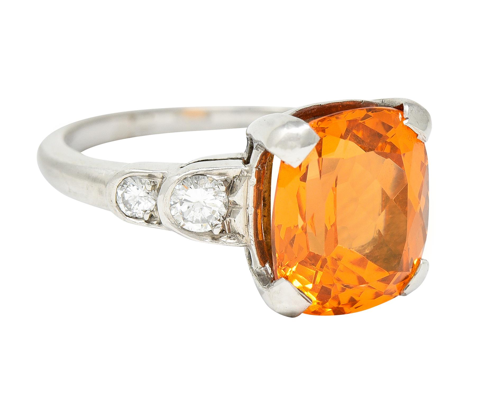 Featuring a mixed cushion cut spessartite garnet weighing 5.41 carats

Eye clean with strong and uniform orange color

Basket set and flanked by stylized scallop stepped shoulders

Accented by round brilliant cut diamonds weighing approximately 0.25