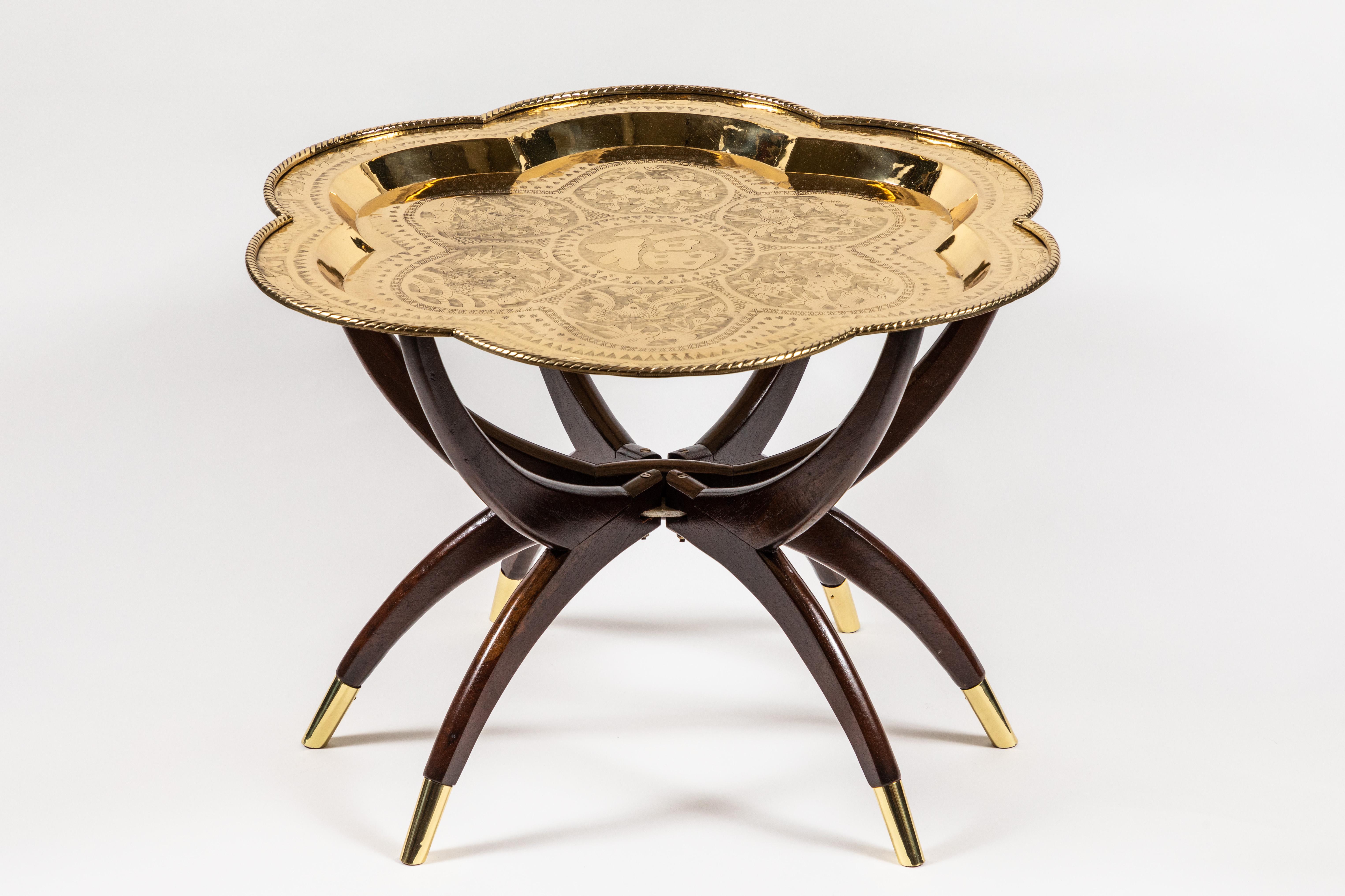 This little mid-century folding tray table with brass tipped spider legs and flower-shaped tray has a lot of character and interest. Newly refinished and polished, the hinged spider base supports a tray engraved with flora and fauna, rabbits and