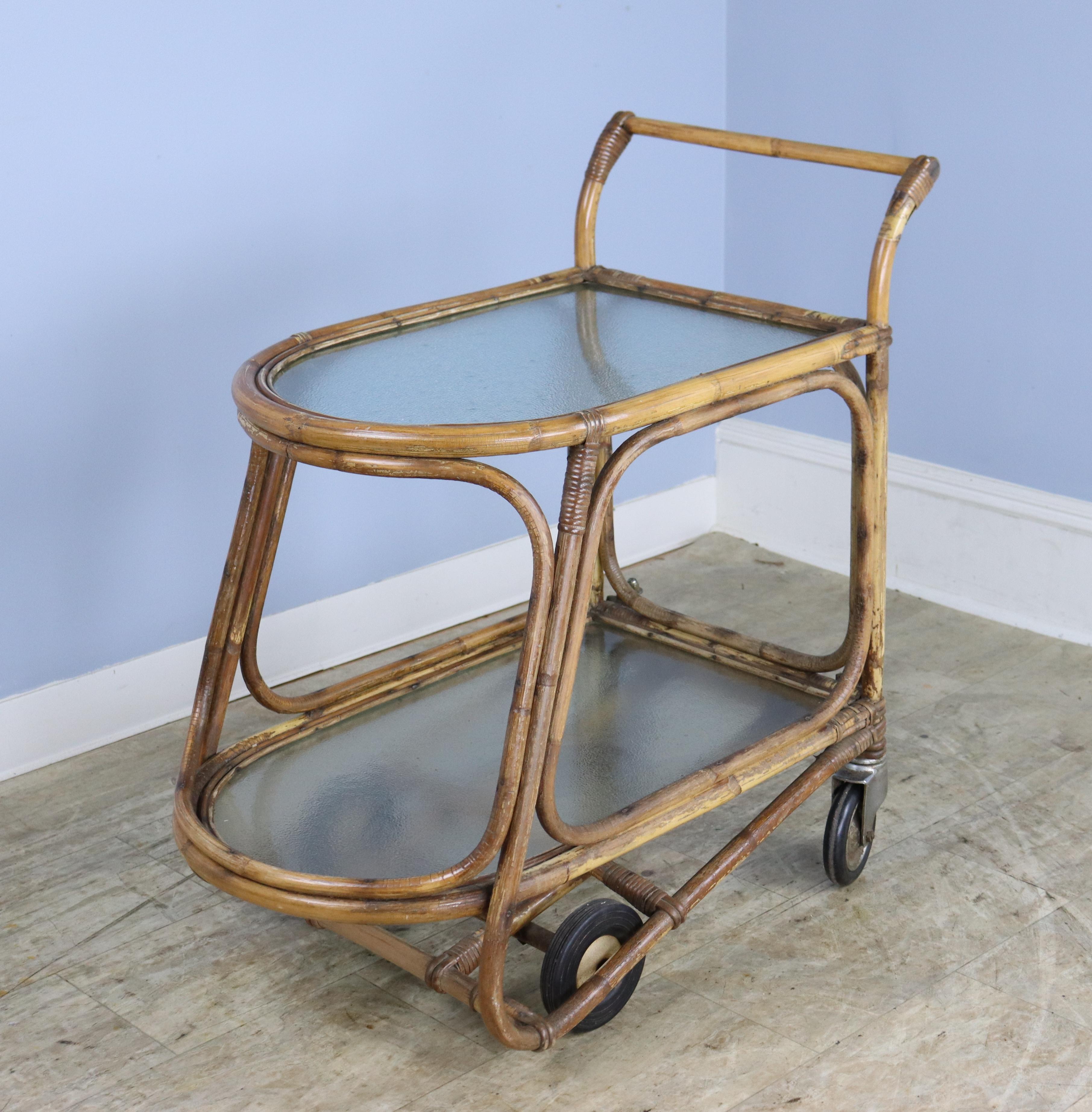 A vintage split cane bamboo drinks trolley.  Wonderful shape with glass shelves, approximately 16 inches in height apart.  The trolley is good heavy quality and runs smoothly on black rubber wheels.  The caning is in fair condition, with areas