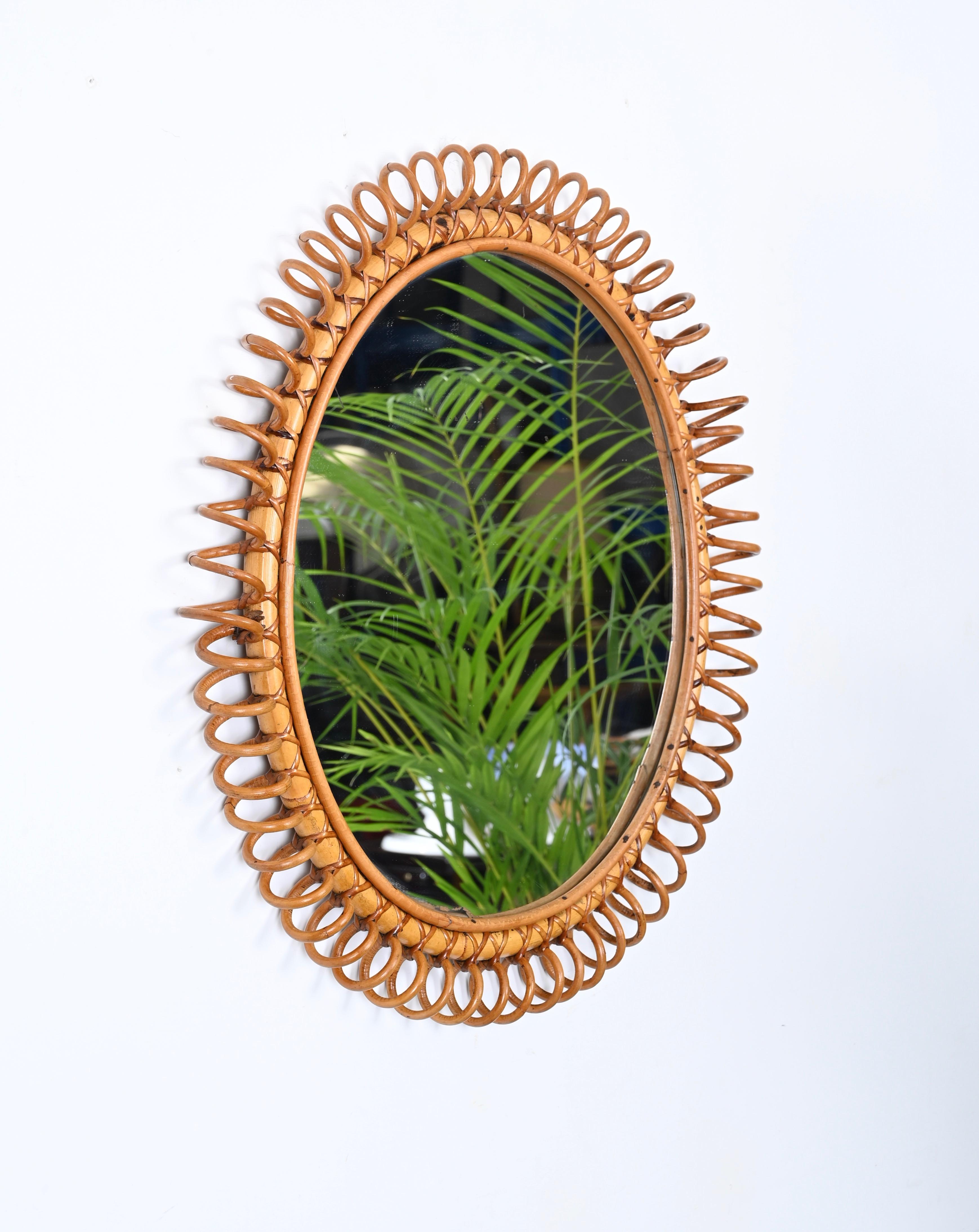 Merveilleux grand miroir de forme ronde du milieu du siècle en rotin, bambou et osier courbé. Cette pièce fantastique a été conçue en Italie dans les années 1960 dans le style de la Côte d'Azur. 

Ce joli miroir présente un superbe cadre en forme de