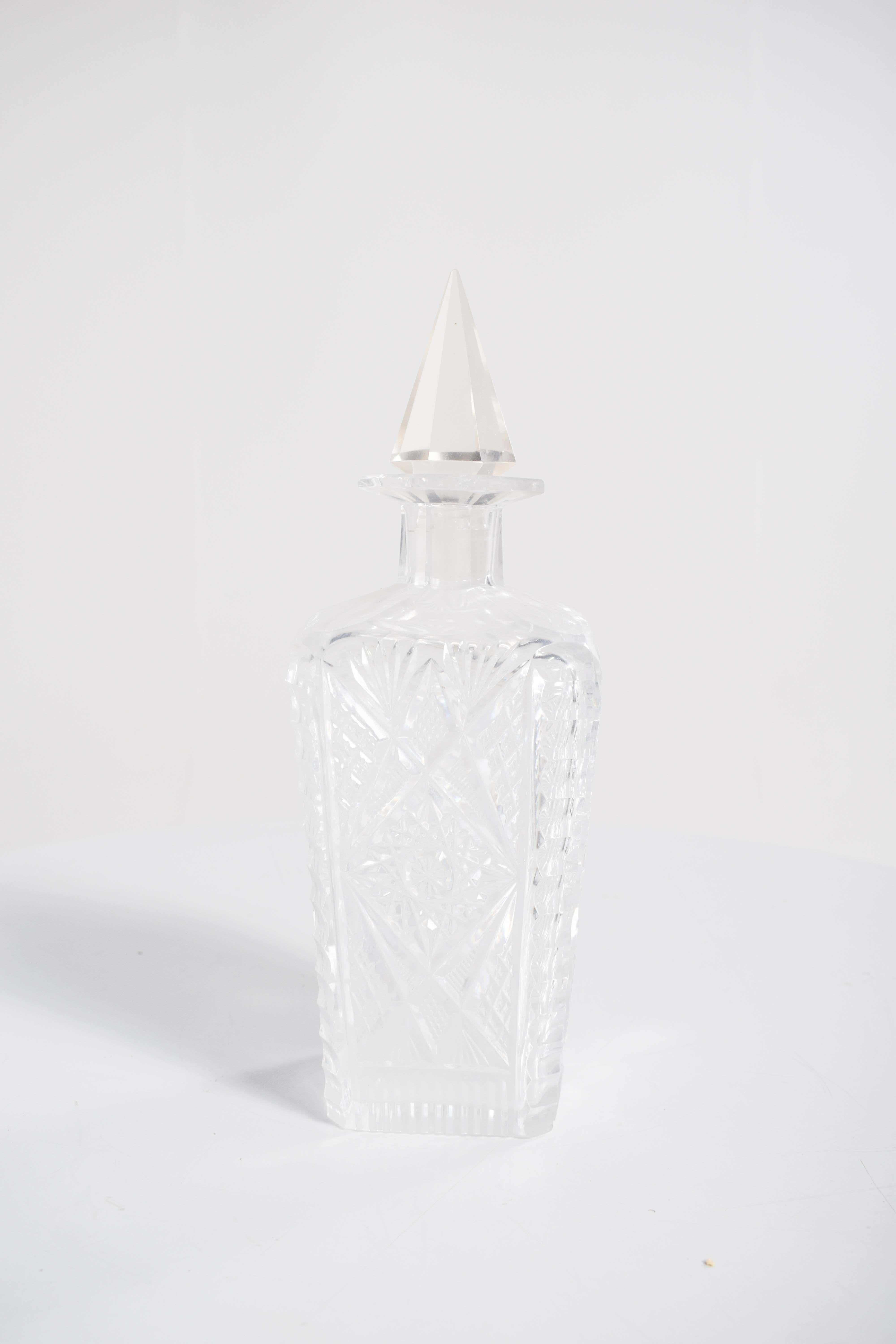 This square bottle of liquor, crafted from cut glass, is a sophisticated and elegant piece designed to make a statement. The bottle itself has sharp, clean lines, with the square shape lending it a modern and geometric appeal. The cut glass creates
