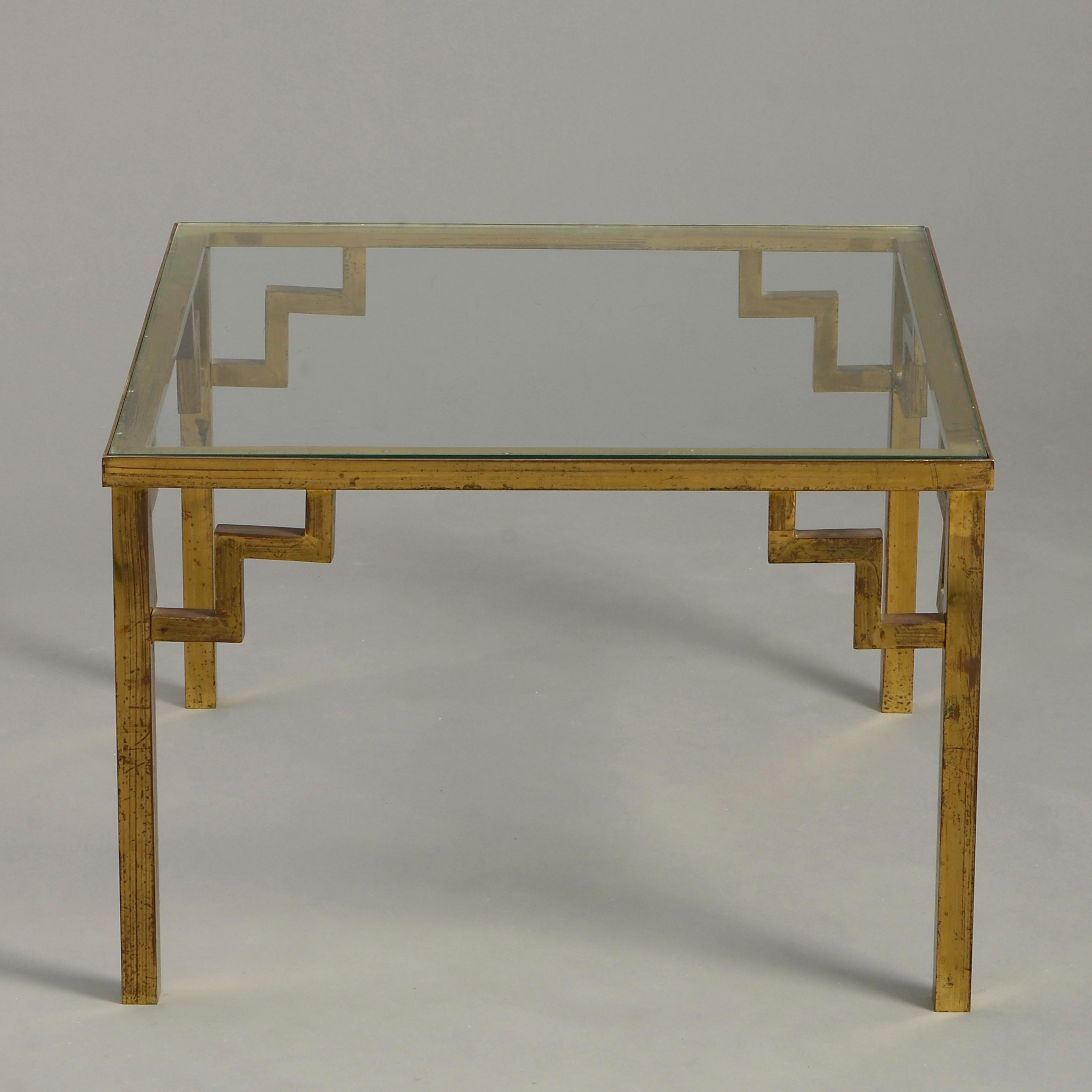 A mid-20th century low table or coffee table of square form, the glass top set within a frame supported by square legs headed by pierced brackets.