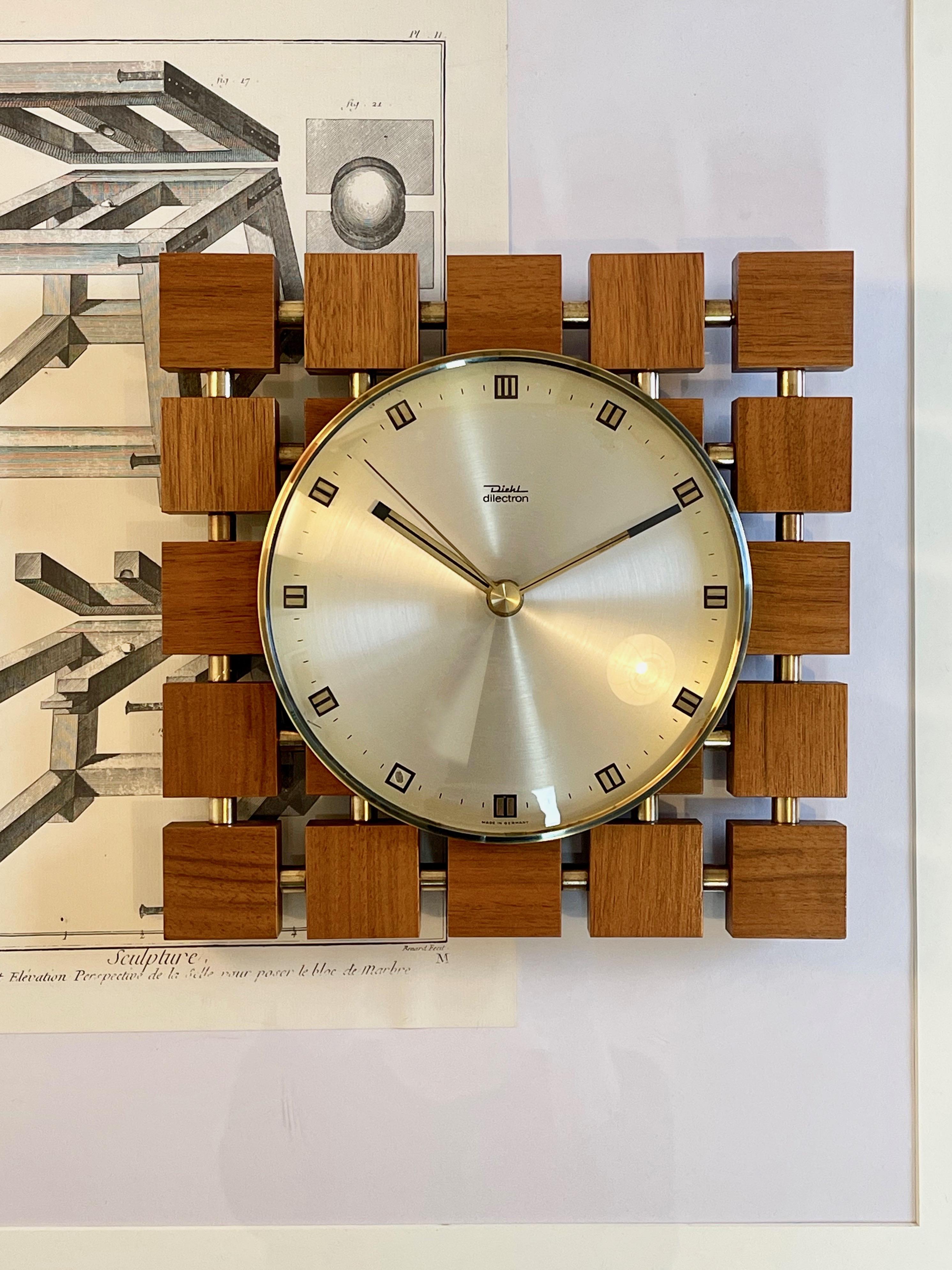 Funky and square shaped design by one of Germanies mid- and late century clock makers Diehl.
Made in the late 60s, early 70s.
Here a fun design from teak and golden chrome connectors, fish eye glass and round aluminum dial with golden hue.
The Diehl