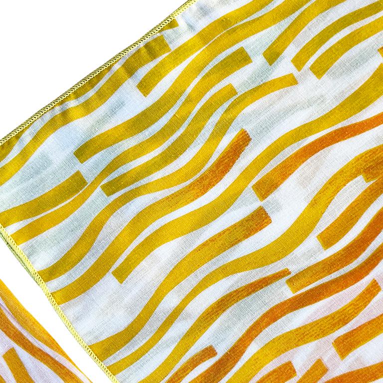 A set of four square fabric dinner napkins with orange and yellow design. 

Dimensions:
17