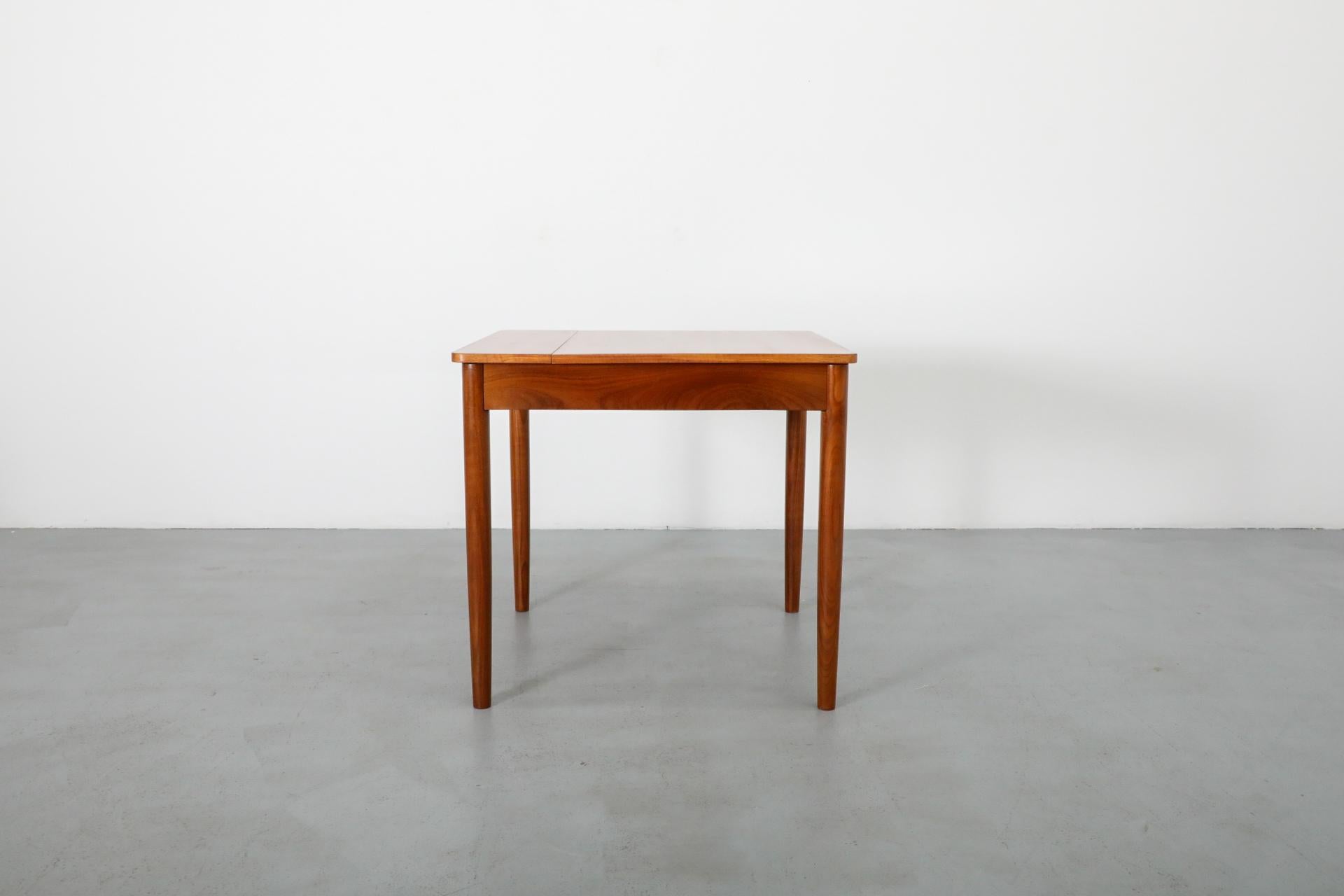 Mid-Century teak dining table with rounded corners and tapered legs. A traditionally styled dining table perfect for a nook with the versatile option of party leaf. In original condition with wear consistent with age and use.